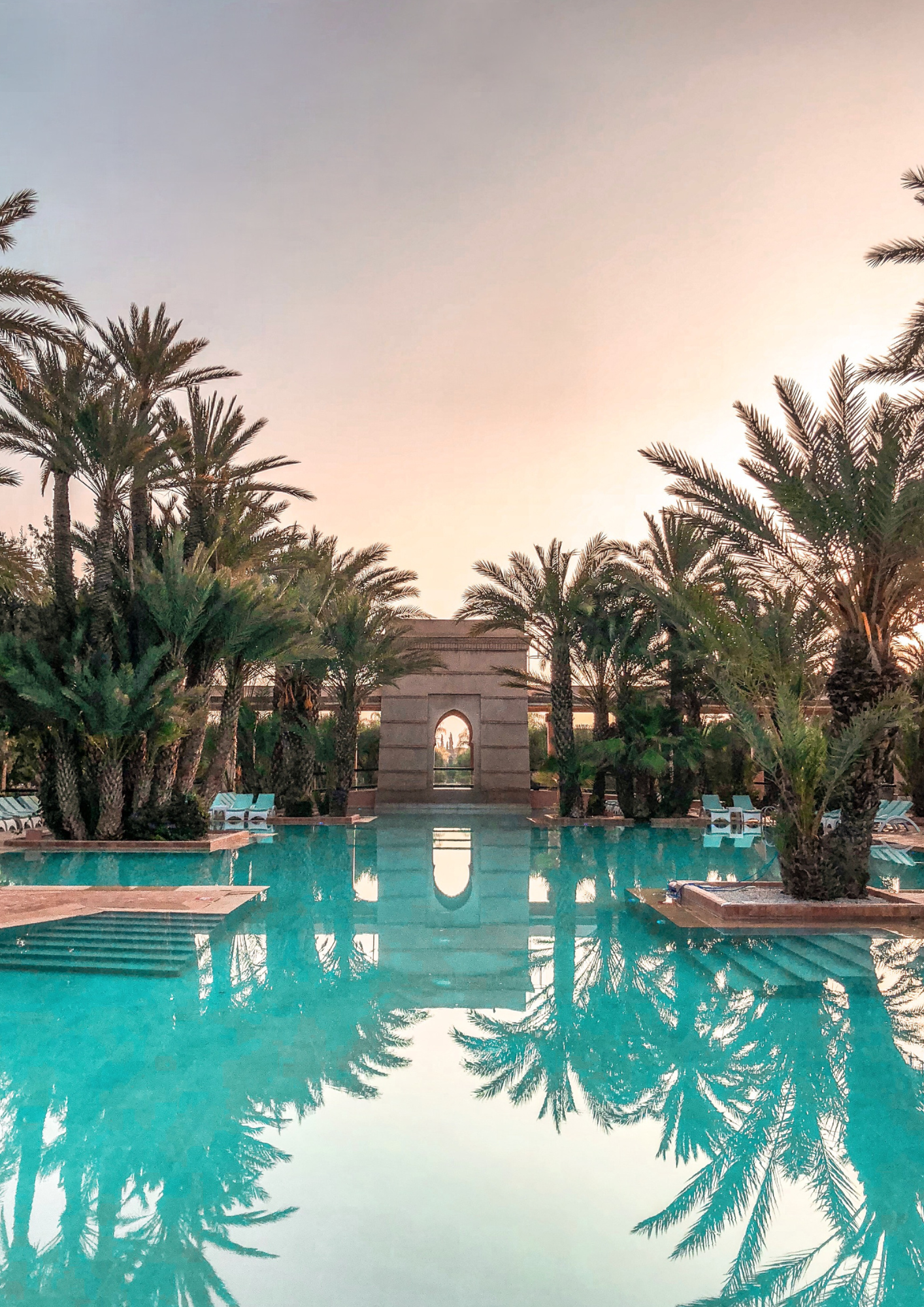 zwembad omringd door palmbomen bij zonsondergang