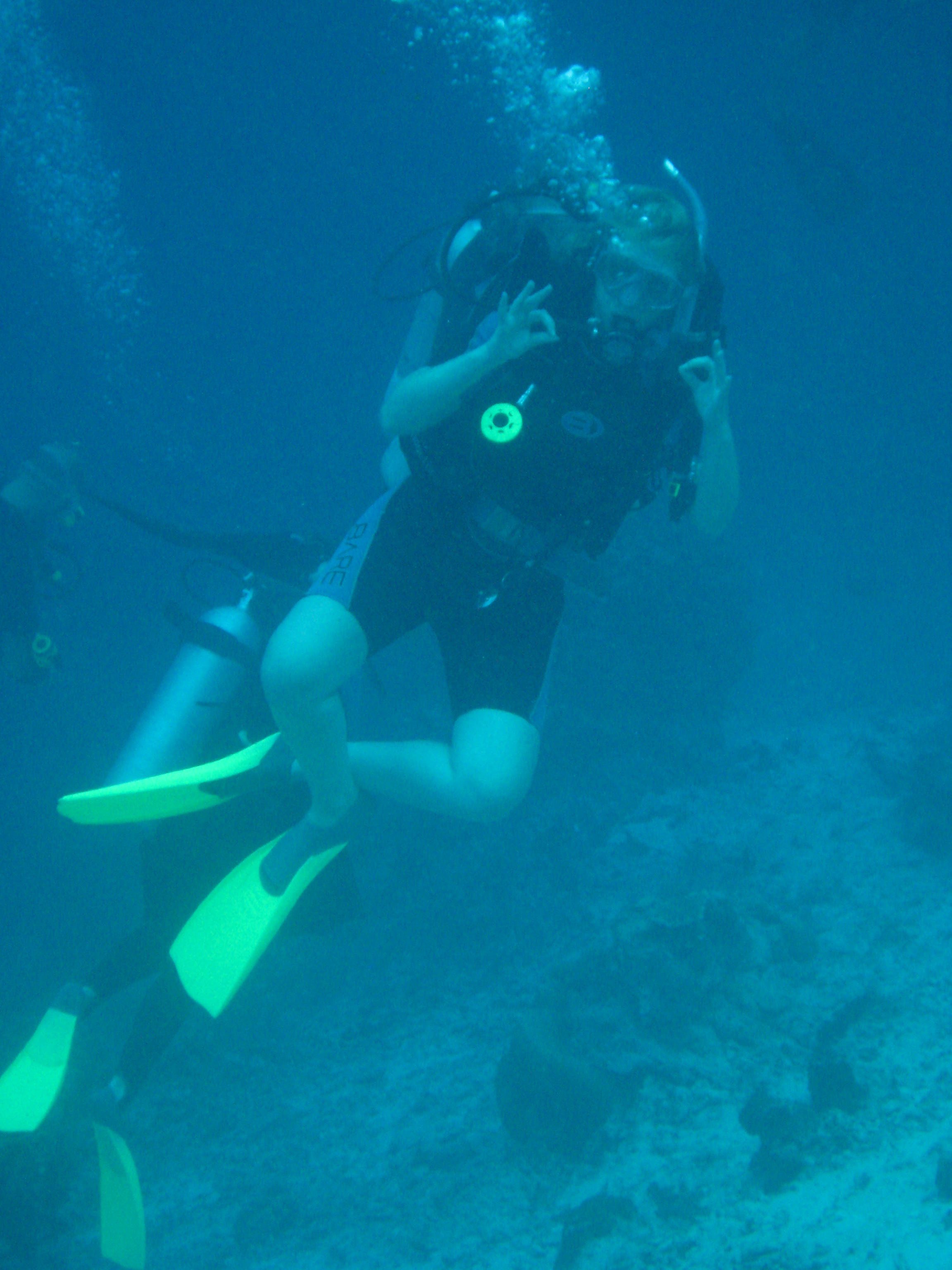 Persoon die duikt maakt het OK-teken met beide handen.