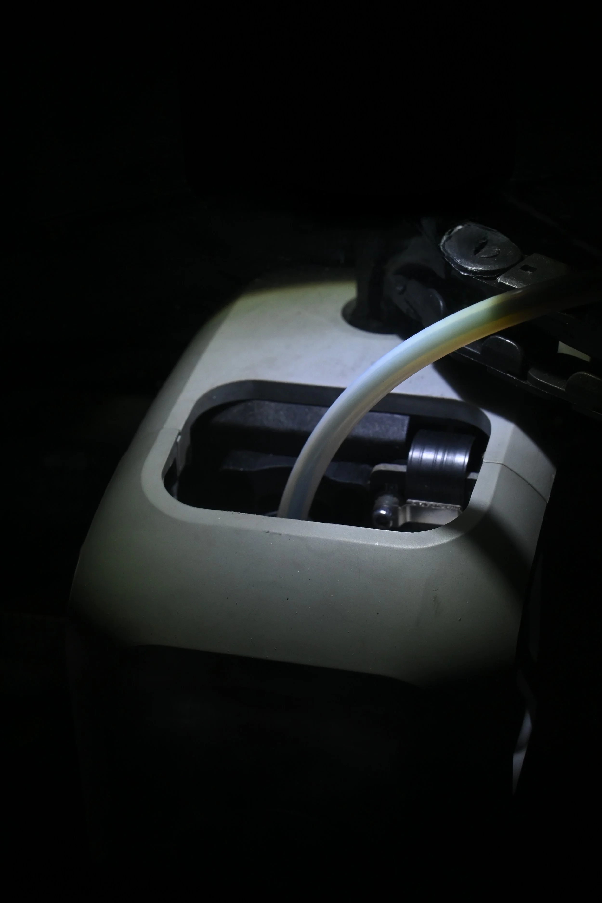 Close-up of a sewing machine with the needle and presser foot visible, illuminated in a dark setting.