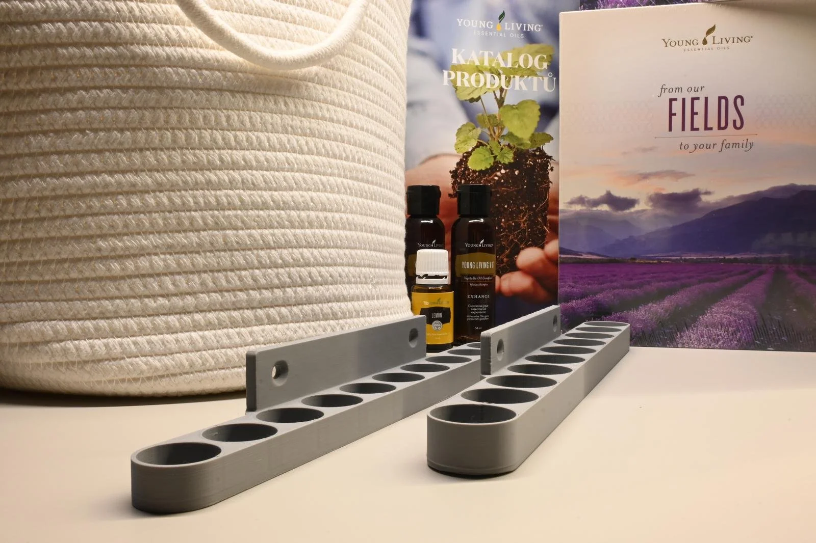 Display of young living essential oils with a coiled white rope in the background, two gray oil bottle holders, and promotional brochures featuring lavender fields, a plant seedling, and the Young Living logo.