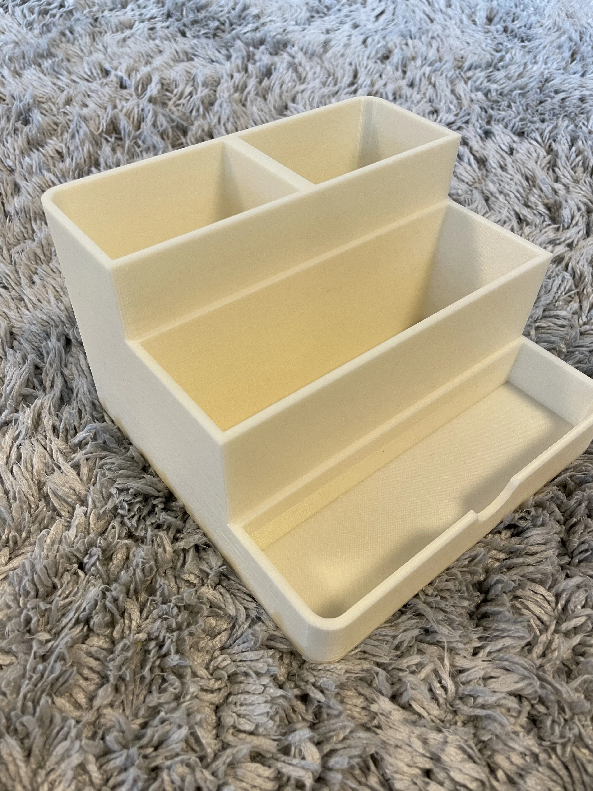 A plastic storage caddy with multiple compartments, resting on a gray shaggy rug.