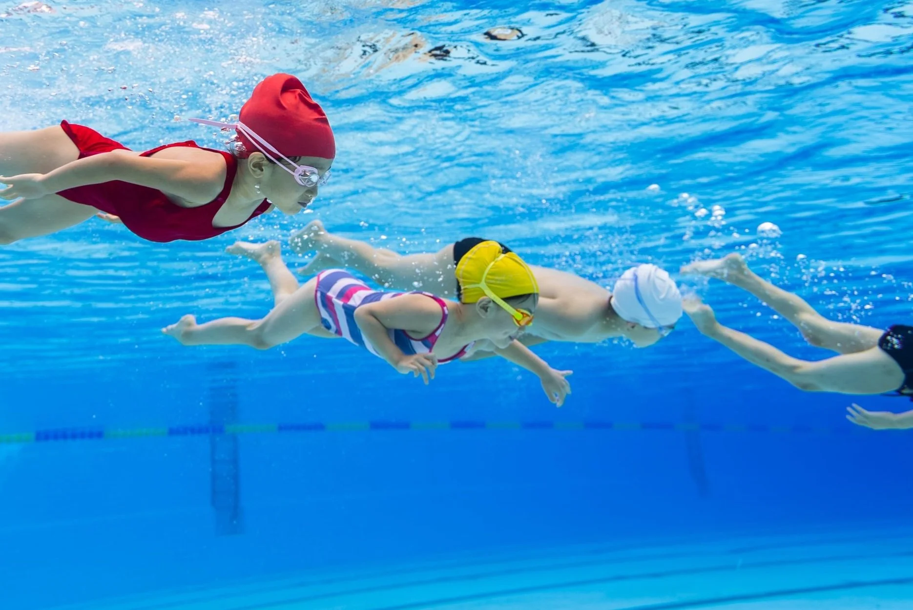 Seitliche Unterwasseraufnahme: Glückliche Kinder schwimmen im Pool