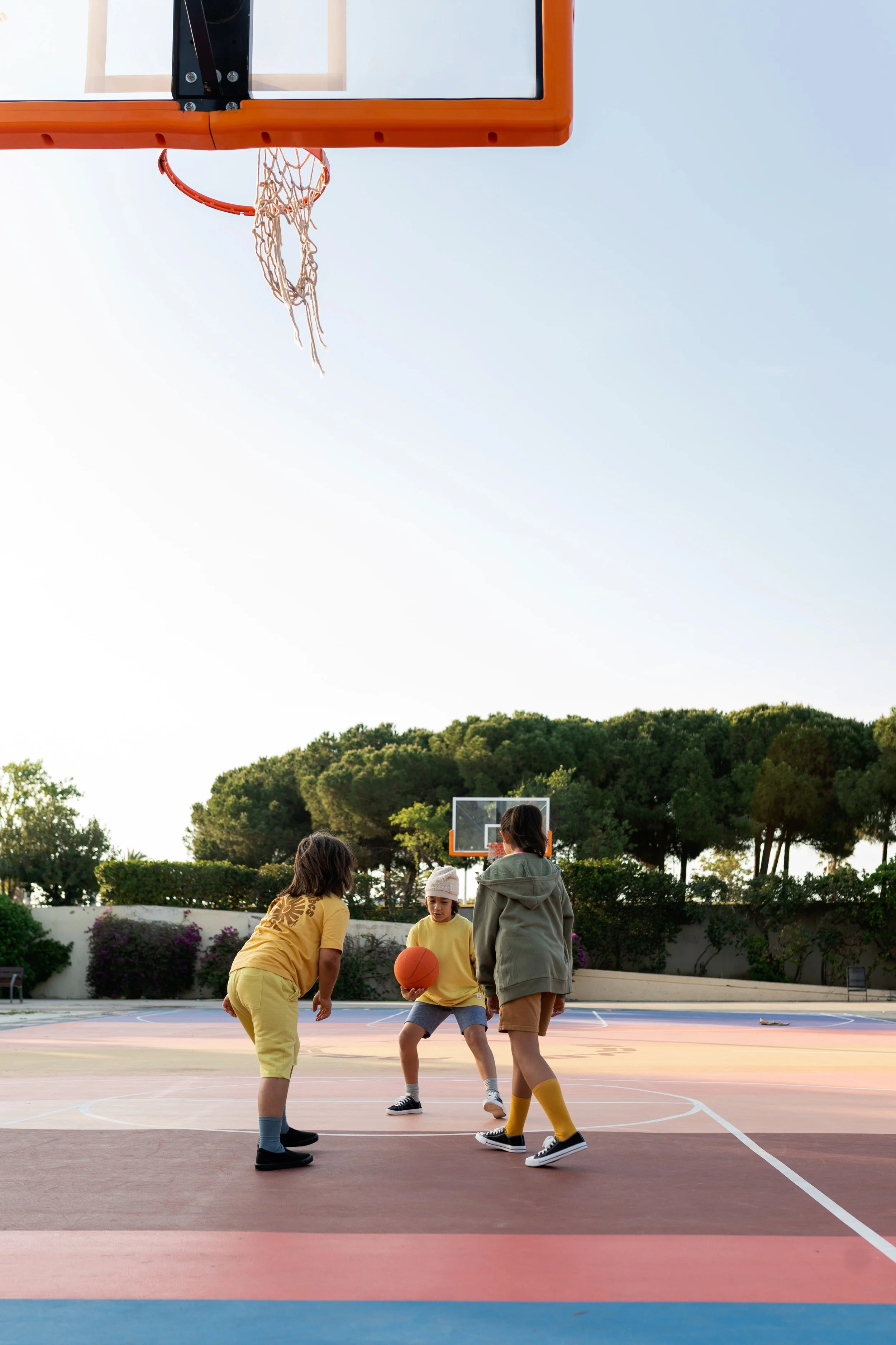Bequem gekleidete Kinder spielen nach der Schule Basketball auf einem Basketballplatz