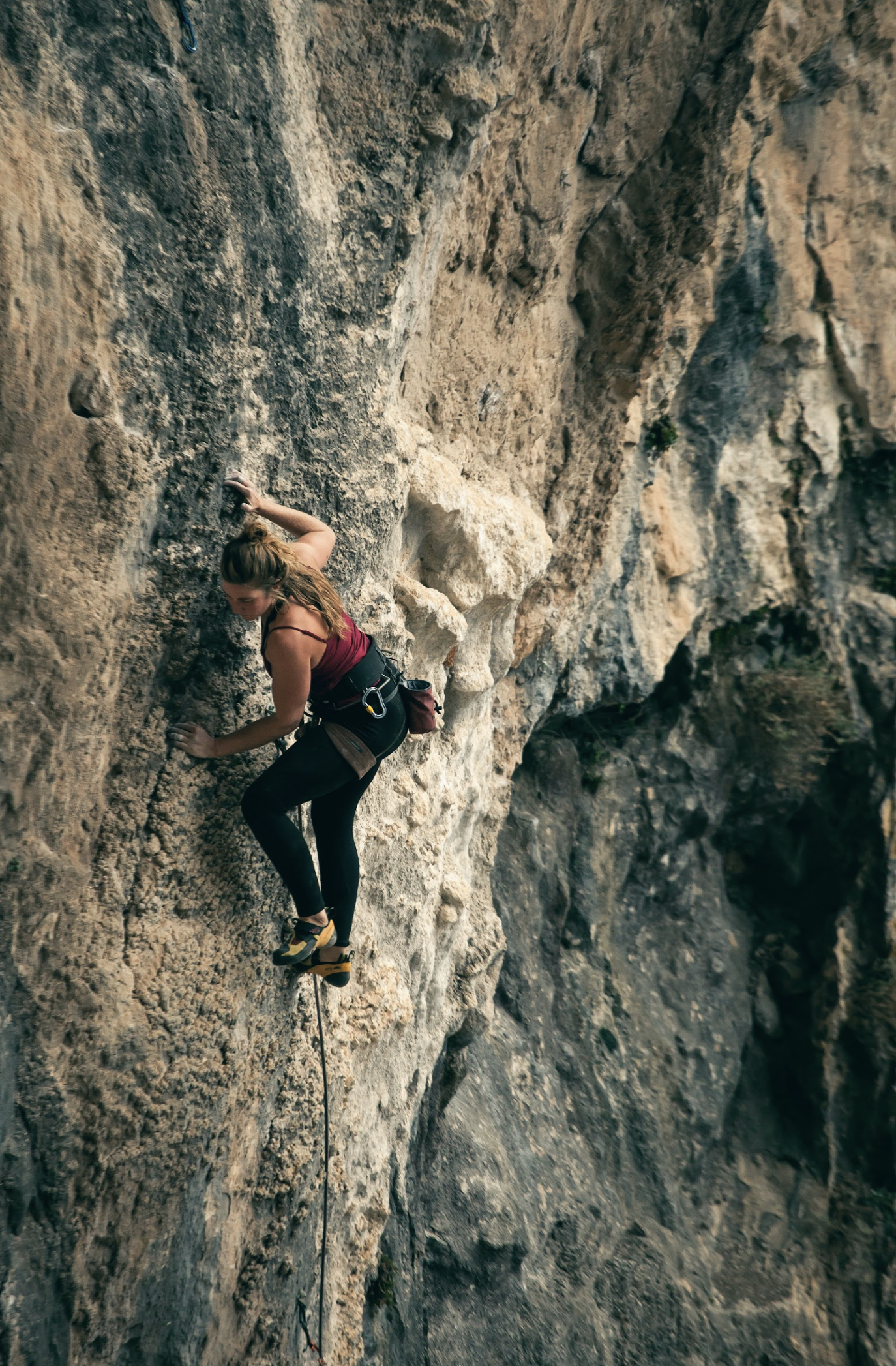 Vrouw klimt aan een rotswand met klimuitrusting in een berghal