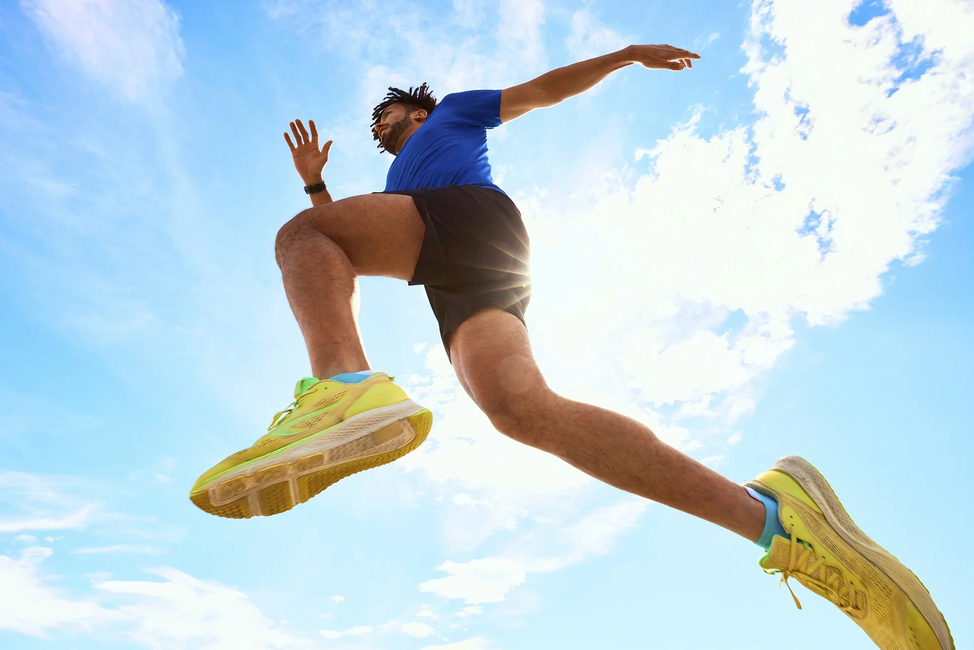Entertainer und Läufer dynamisch von unten fotografiert springt und rennt gerade durch die Sonne mit blauem Himmel für das Try-Challenge Event von TUI Magic Life