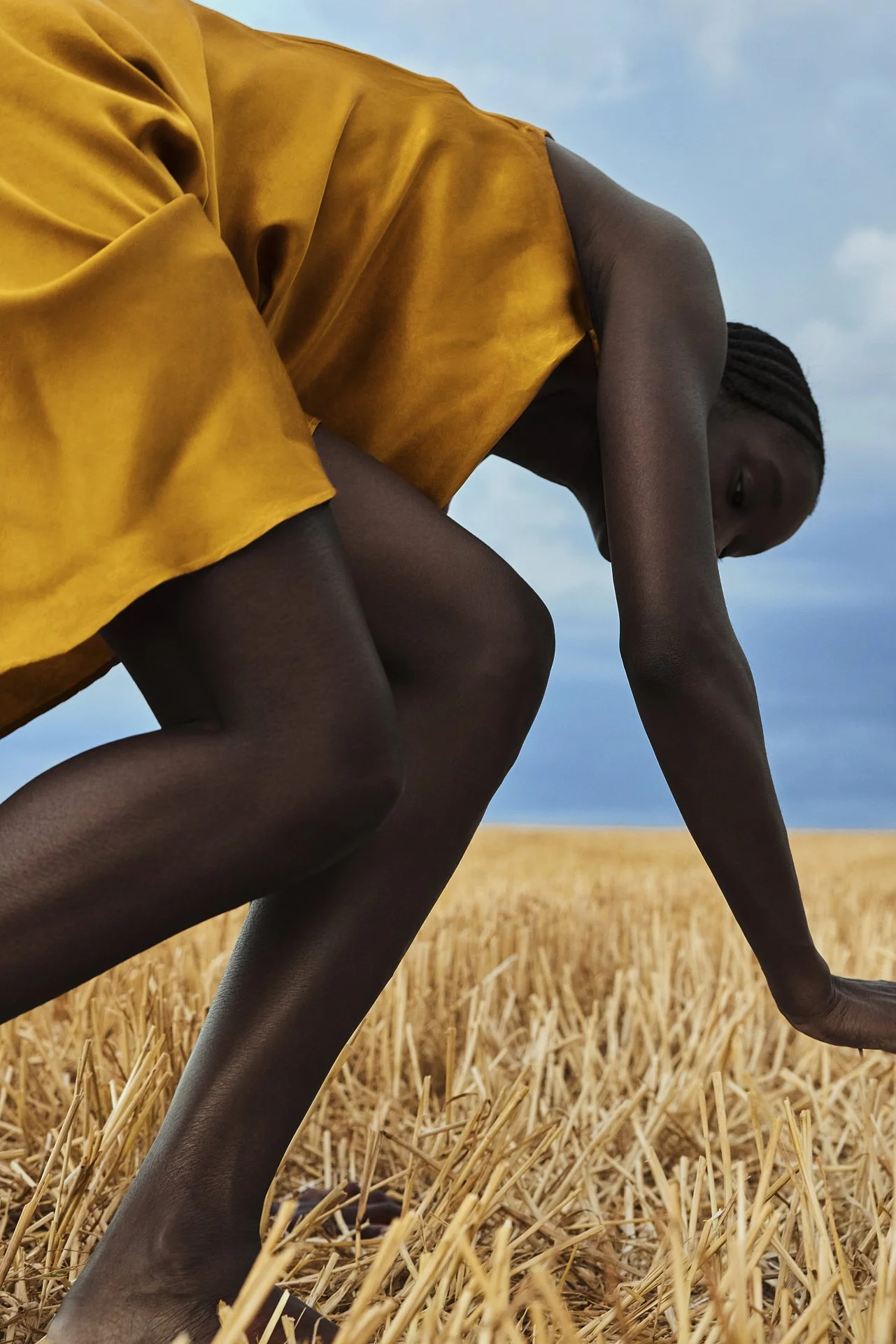 Schwarzes Model in goldenem Kleid klettert läuft durch ein gemähtes Feld auf dem Land in der nähe von Paris