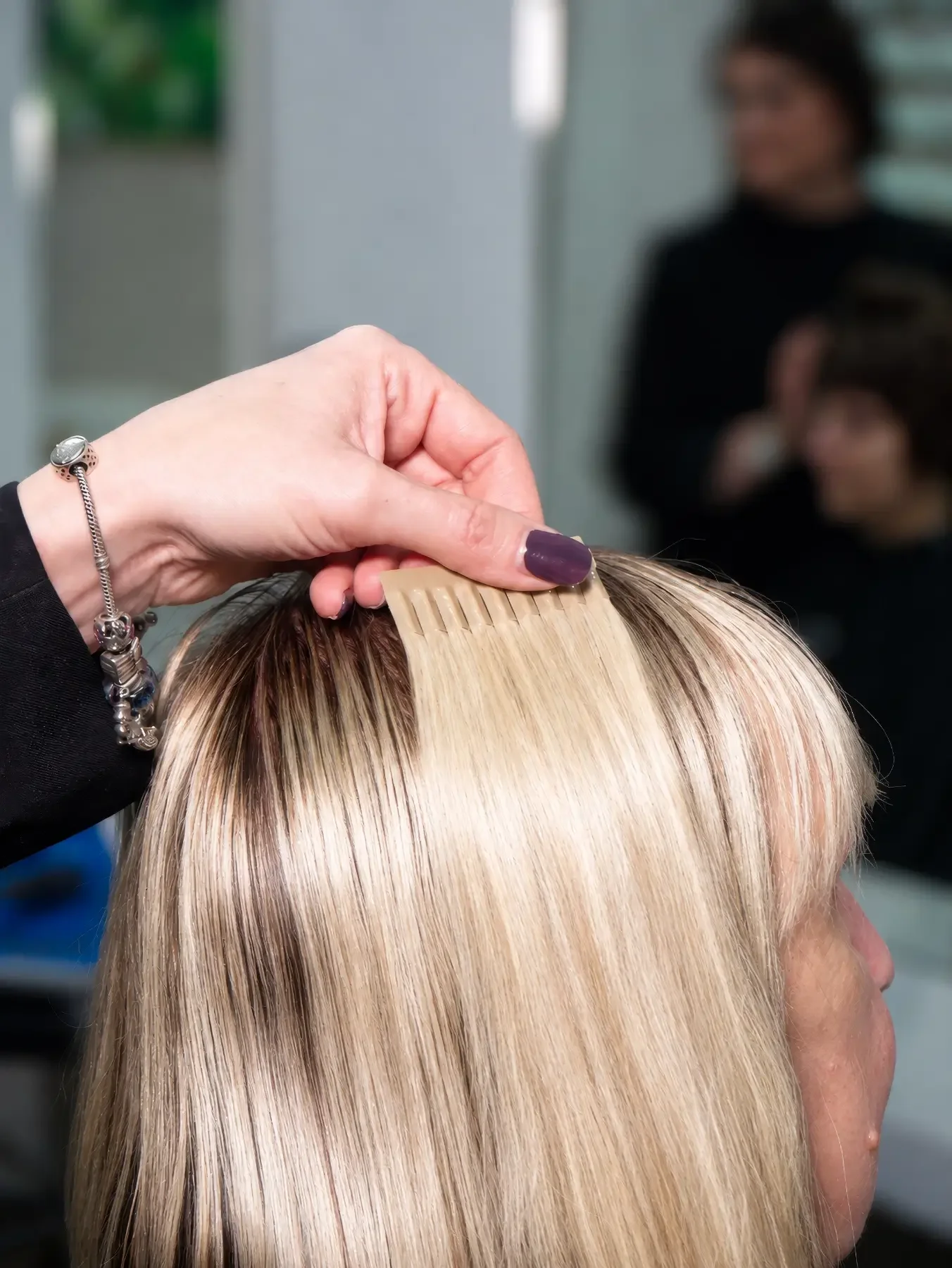 Great Lengths Tape-Extension wird an das blonde Eigenhaar einer Kundin gehalten, um Farbton, Länge und natürlichen Übergang der Haarverlängerung abzustimmen. Garzareck Halle (Saale).