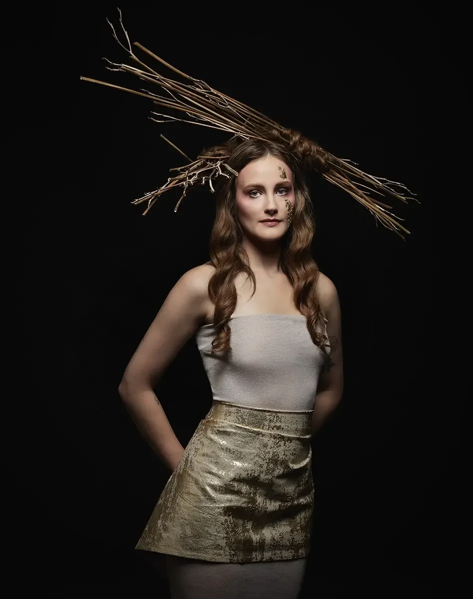Studioporträt mit organischer Avantgarde-Frisur aus Ästen, langen Wellen und natürlichem Editorial-Make-up vor schwarzem Hintergrund aus der Serie „verwurzelt schön“ von Garzareck Halle.