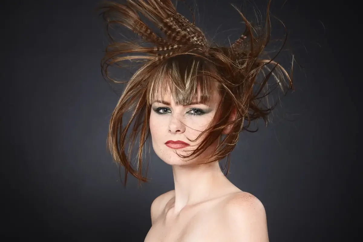 Avantgardistisches Beauty-Porträt mit skulpturalem, dynamischem Hairstyling und geflochtenen Haarstrukturen vor dunklem Studiohintergrund. Garzareck Editorial-Look mit Fokus auf kreative Frisurenkunst, Haut und modernes Fashion-Make-up.