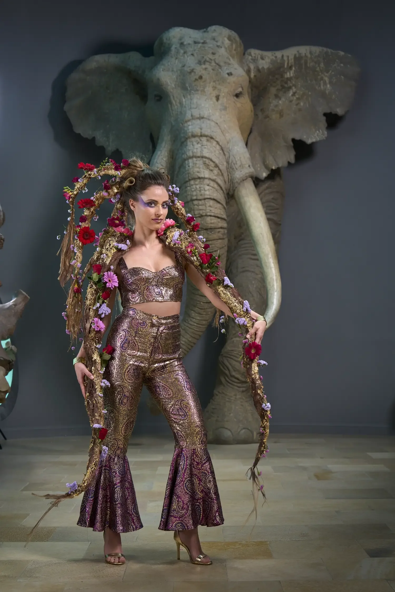 Editorial-Fashionportrait aus der Serie „Botanical Avantgarde“ von Garzareck mit floral inszeniertem Model vor großer Elefantenskulptur im Landesmuseum für Vorgeschichte Halle.
