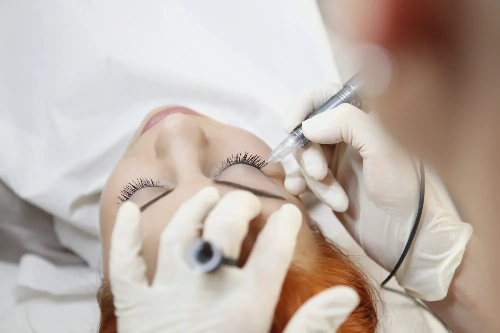 Ariane Garzareck führt eine Permanent-Make-up-Lidstrichbehandlung mit modernem Pigmentiergerät durch. Die Kundin liegt entspannt während der präzisen Behandlung im Cosmetics-Studio in Halle (Saale).