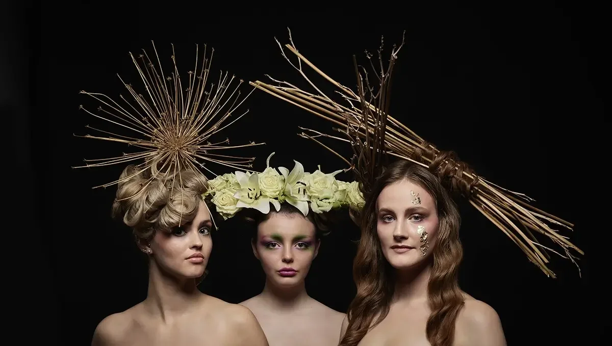 Drei Frauen mit avantgardistischen Frisuren aus Ästen, Blüten und organischen Naturformen in einem kunstvollen Editorial-Studioporträt der Serie „verwurzelt schön“ von Garzareck Friseur Halle.
