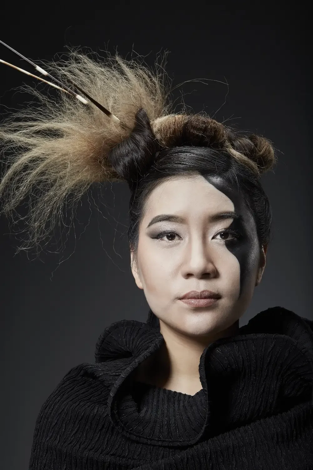 Künstlerisches Avantgarde-Porträt aus der Black-&-White-Fotoaktion mit grafischem Make-up und skulpturalem Haarstyling vor dunklem Hintergrund, Galeriebild von Garzareck in Halle (Saale).