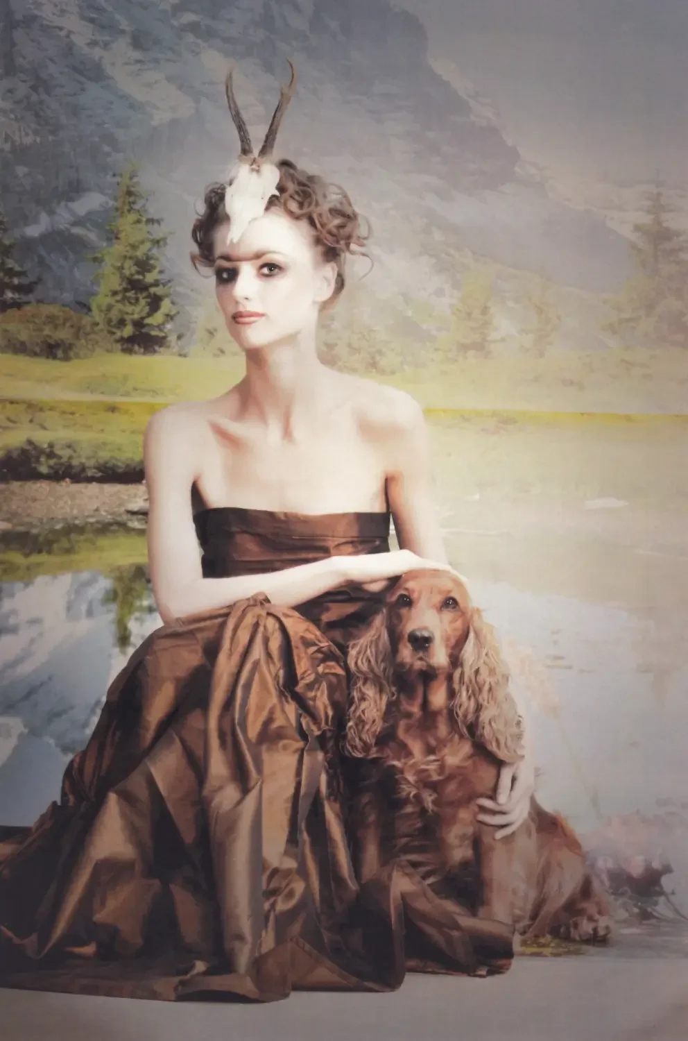 Mystisches Editorial-Porträt mit Hirschschädel-Styling und Hund vor alpiner Landschaftskulisse.