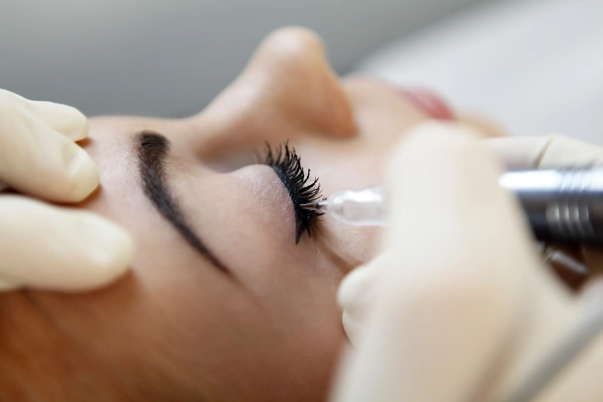 Detailaufnahme einer Permanent-Make-up-Lidstrichbehandlung. Ariane Garzareck pigmentiert den oberen Wimpernkranz einer Kundin mit höchster Präzision in ihrem Cosmetics-Studio in Halle (Saale).
