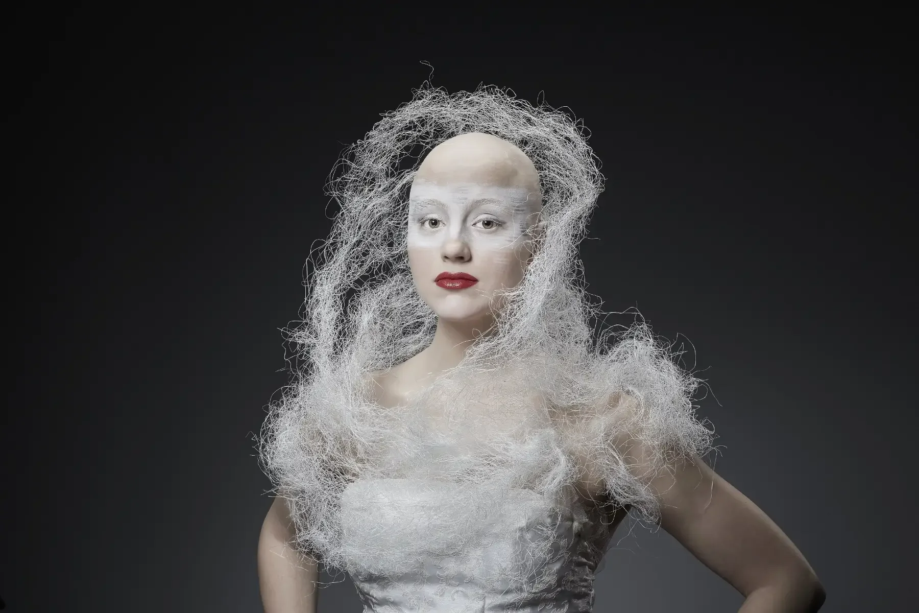 Zentral aufgenommenes Avantgarde-Porträt aus der Black-&-White-Fotoaktion mit weißer, netzartiger Gesichts- und Körperinszenierung, rotem Lippenakzent und klarer Haltung vor dunklem Hintergrund bei Garzareck in Halle (Saale).