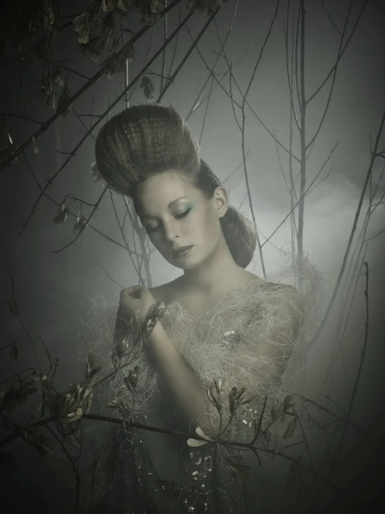 Verträumtes Editorial-Beauty-Porträt mit skulpturaler Hochsteckfrisur, weichen Texturen und zarten Zweigen im Nebelwald. Die reduzierte Farbwelt und das diffuse Licht verleihen der Szene eine elegante, melancholische Garzareck-Atmosphäre.