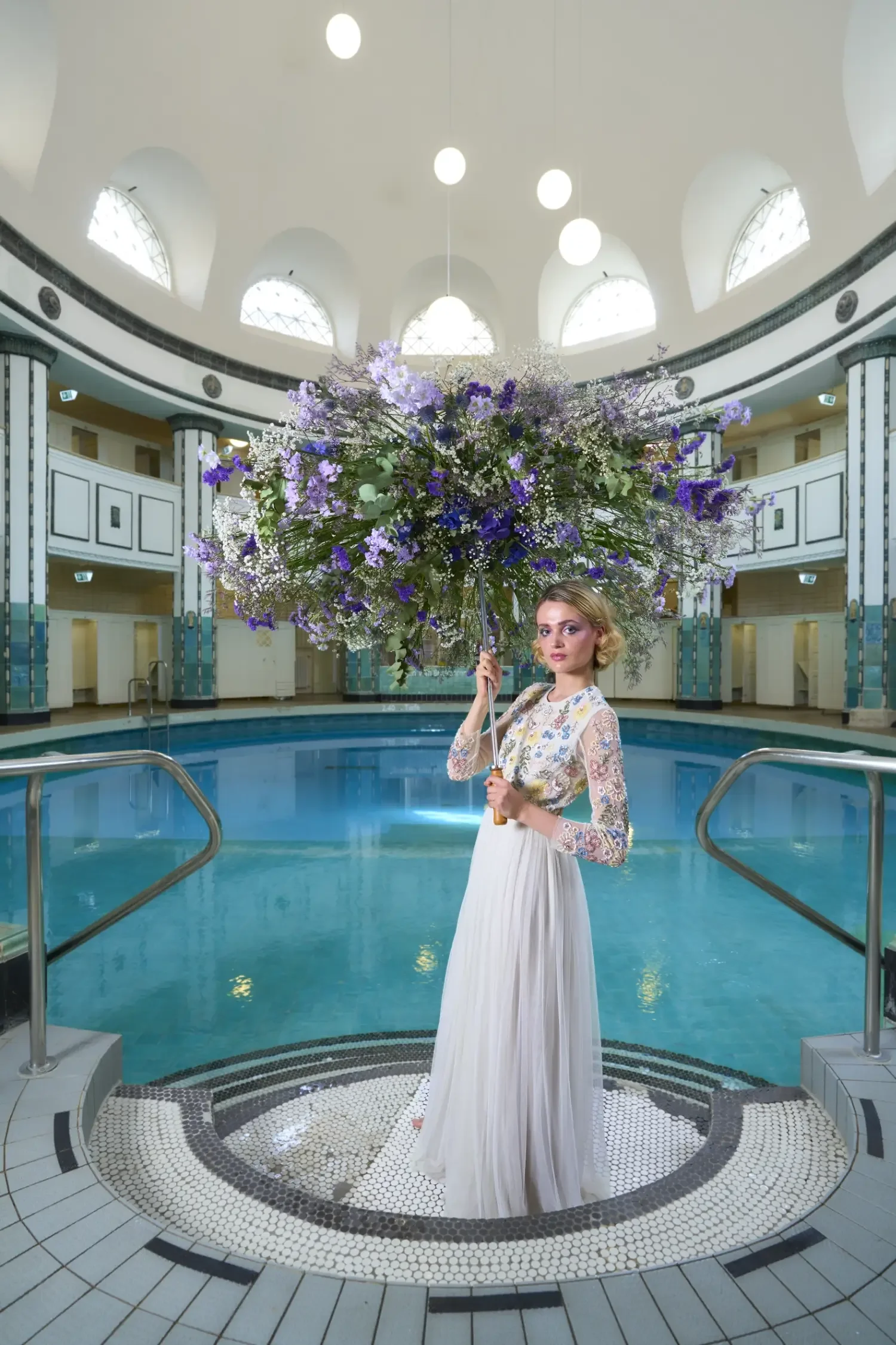 Editorial-Modefotografie aus der Serie „Botanical Avantgarde“ von Garzareck mit Model und übergroßem floralem Schirm im historischen Stadtbad Halle.