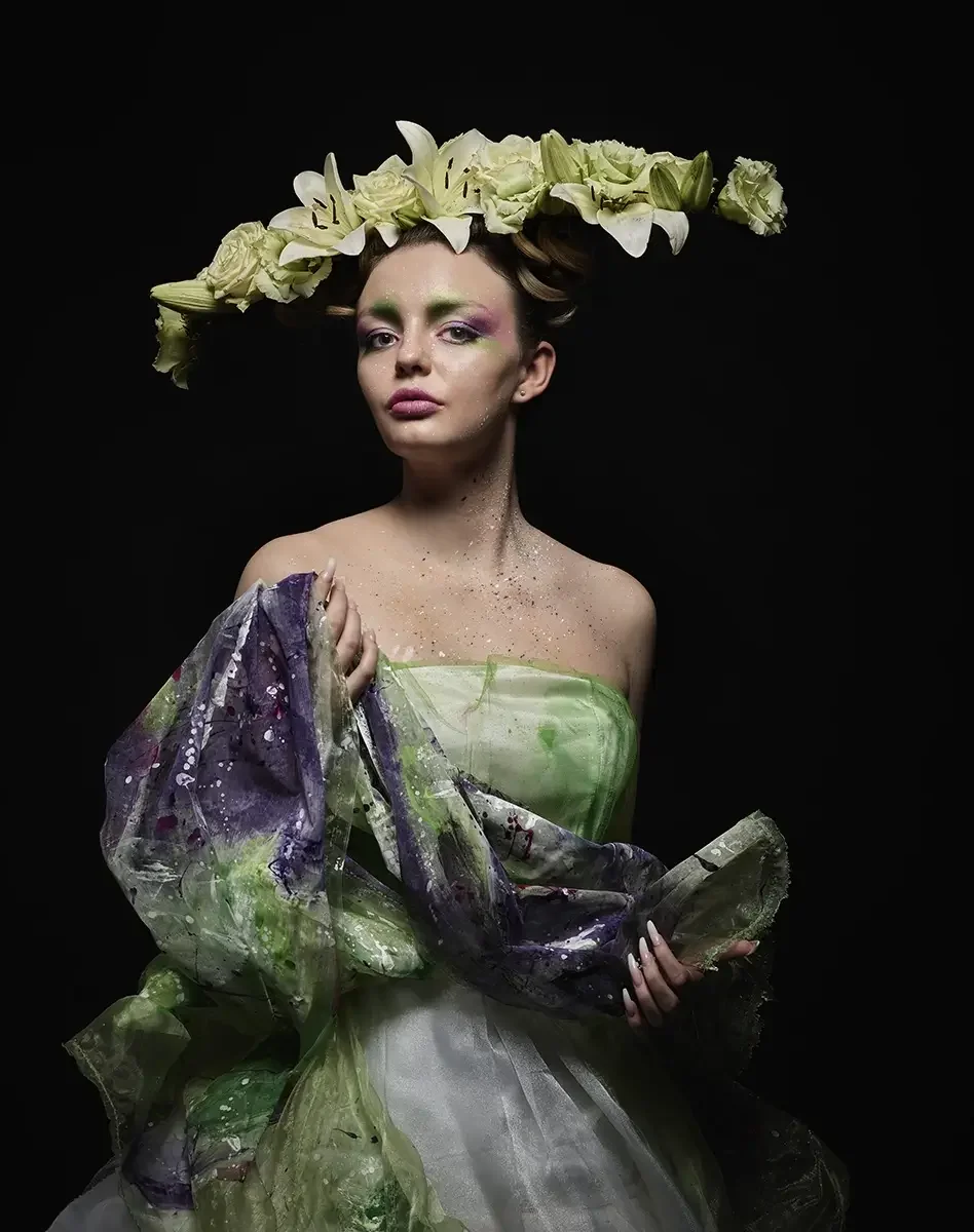 Studioporträt mit floraler Avantgarde-Frisur aus weißen Lilien, künstlerischem Make-up und transparentem Couturekleid vor schwarzem Hintergrund aus der Serie „verwurzelt schön“ von Garzareck Halle.