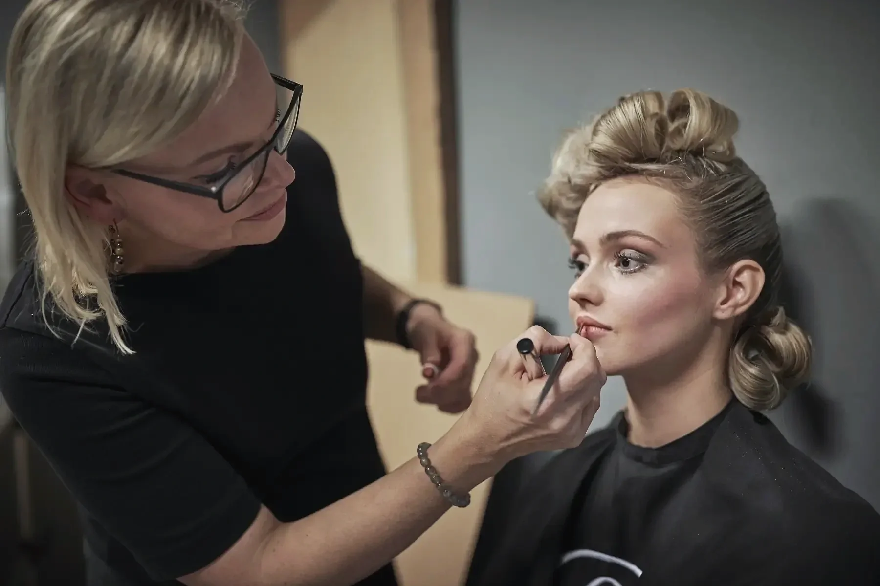 Visagistin Ariane Garzareck verleiht einem Model den letzten Feinschliff für das Editorial-Fotoshooting „Verwurzelt schön“ mit professionellem Make-up und Hairstyling.