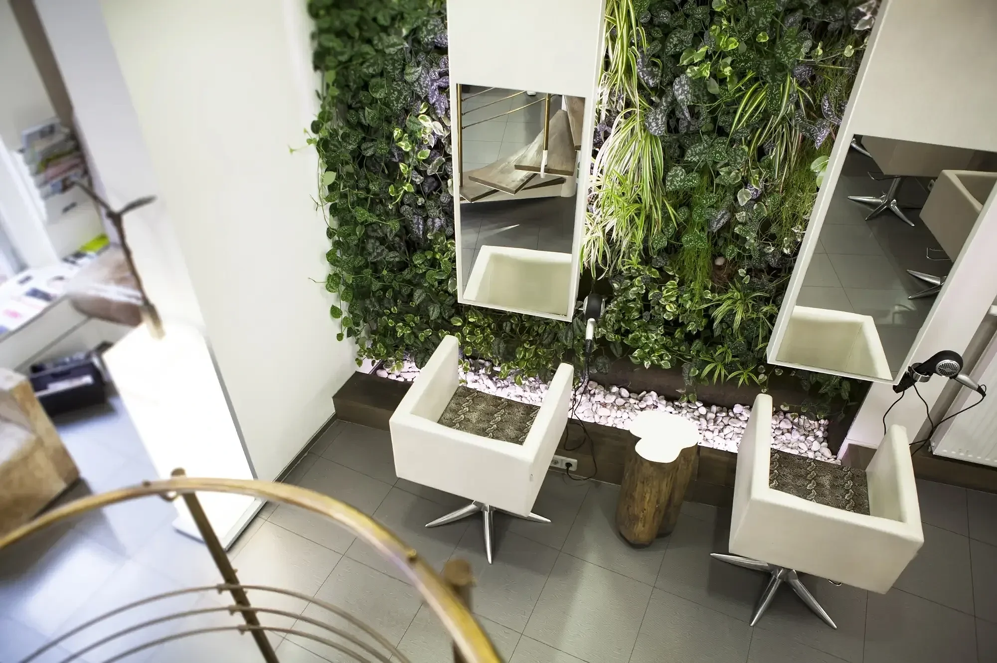 Stylingbereich mit begrüntem Wanddesign, Spiegeln und Friseurplätzen im Salon von Garzareck Coiffeur & Cosmetics in Halle (Saale).