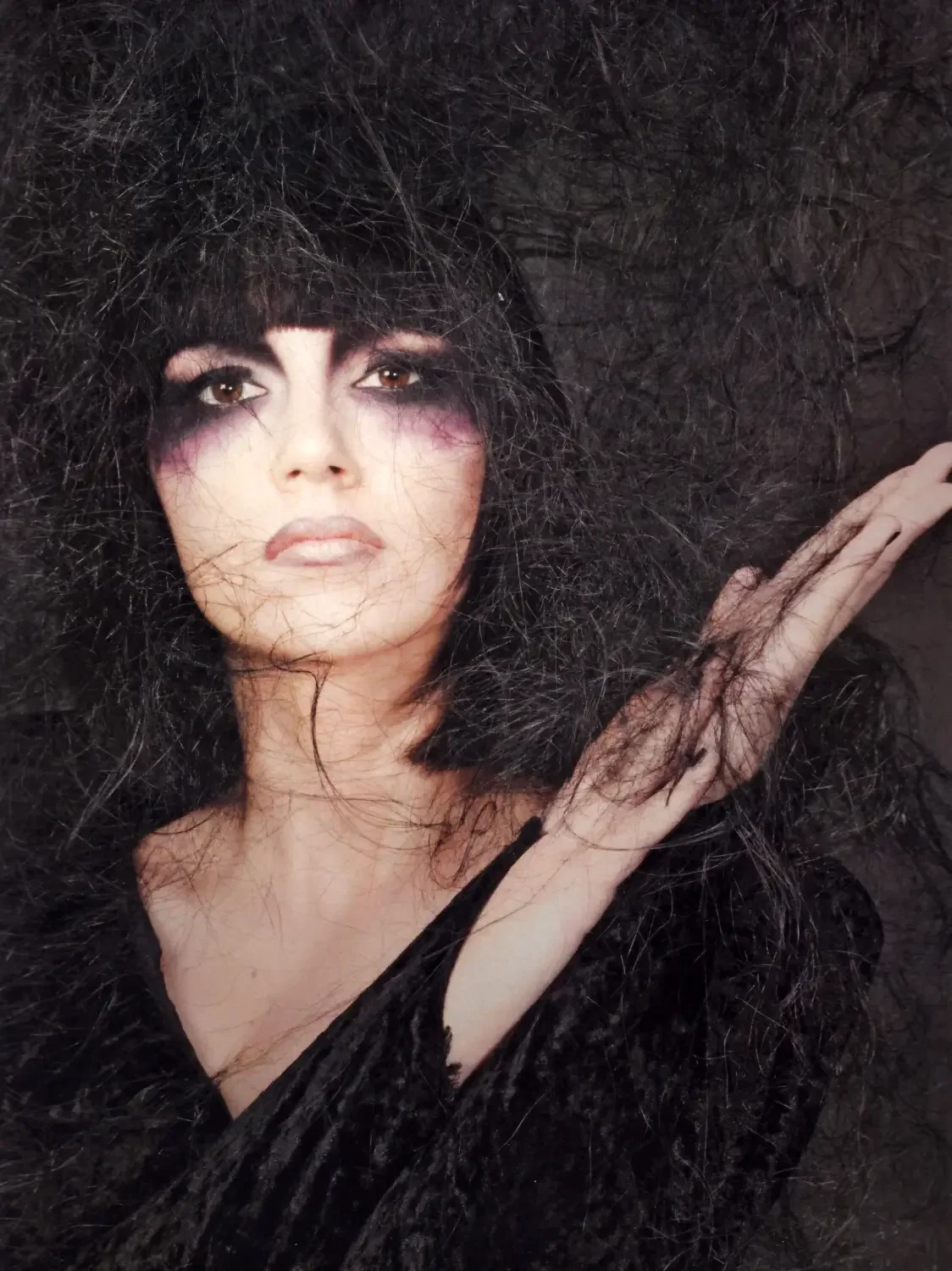 Avantgarde-Beauty-Porträt mit schwarzem Volumenhaar und dramatischem Augen-Make-up im Editorial-Stil.