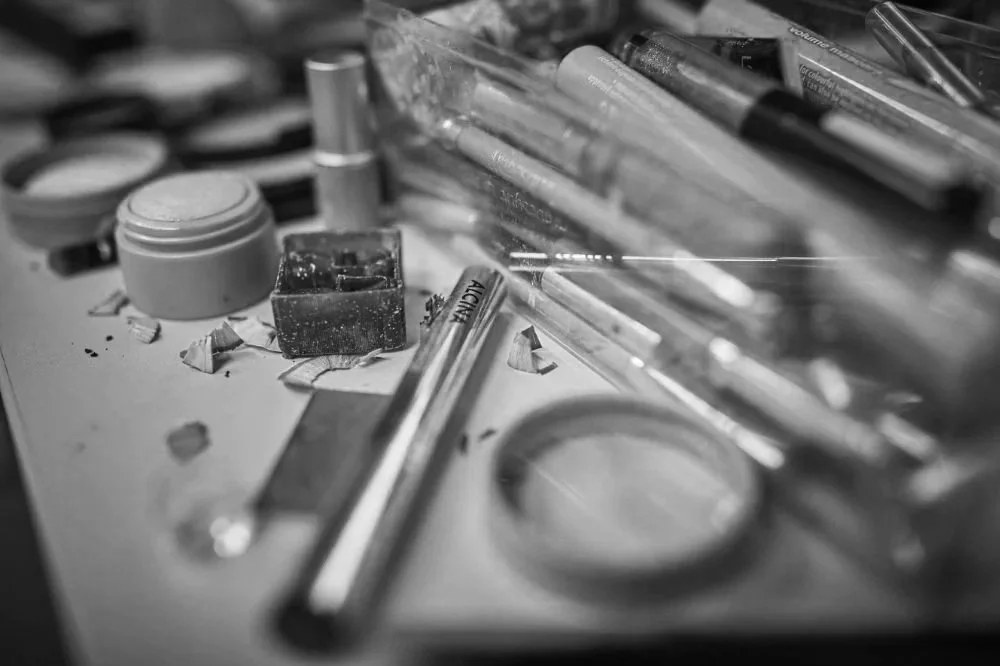 Makeup-Produkte und Kosmetikartikel auf einem Tisch, darunter Lidschatten, Lippenstifte, Pinsel und Kosmetiktücher.