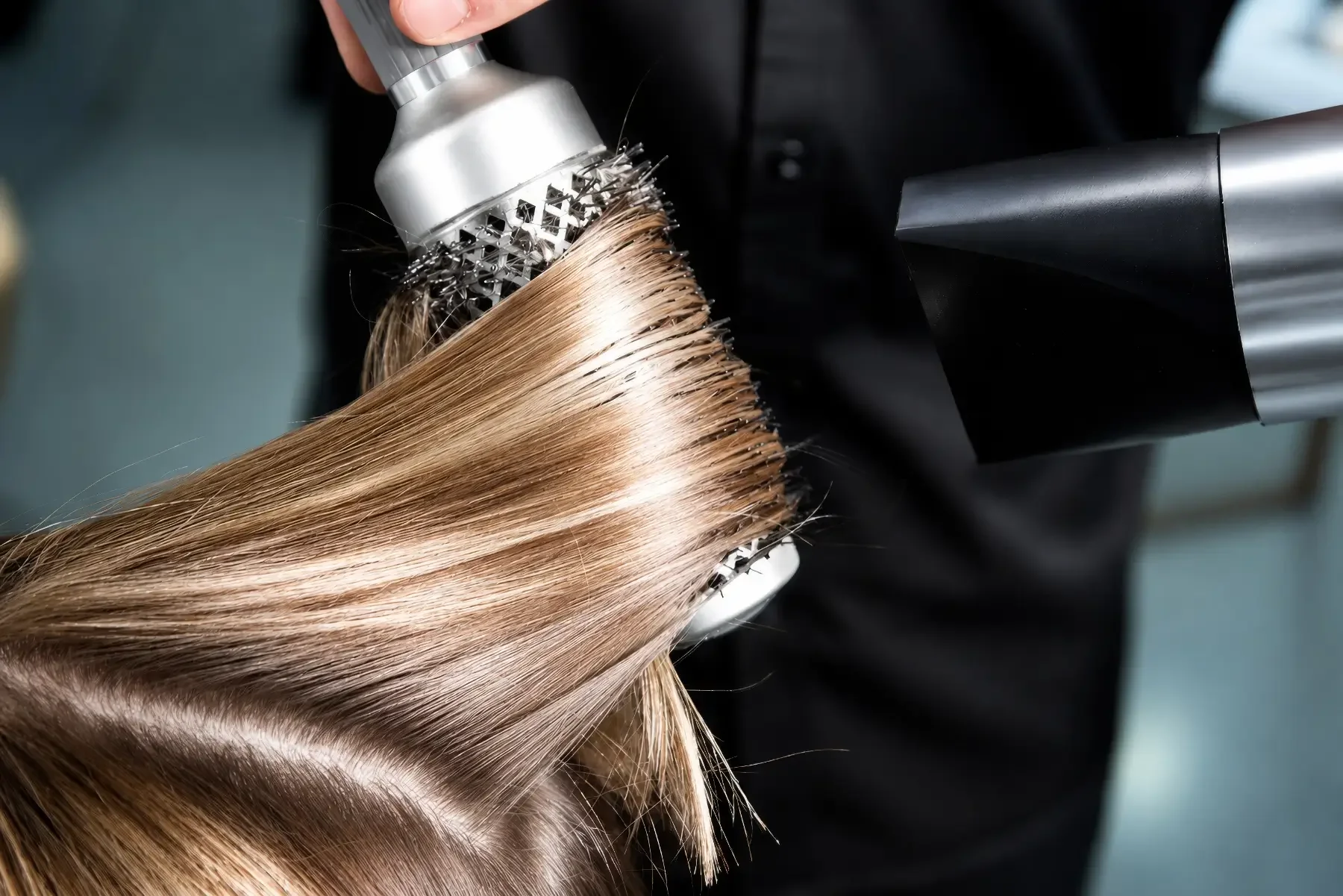 Professionelles Föhnen mit Rundbürste für glattes, glänzendes Haar während eines Coiffeur-Termins bei Garzareck in Halle (Saale).