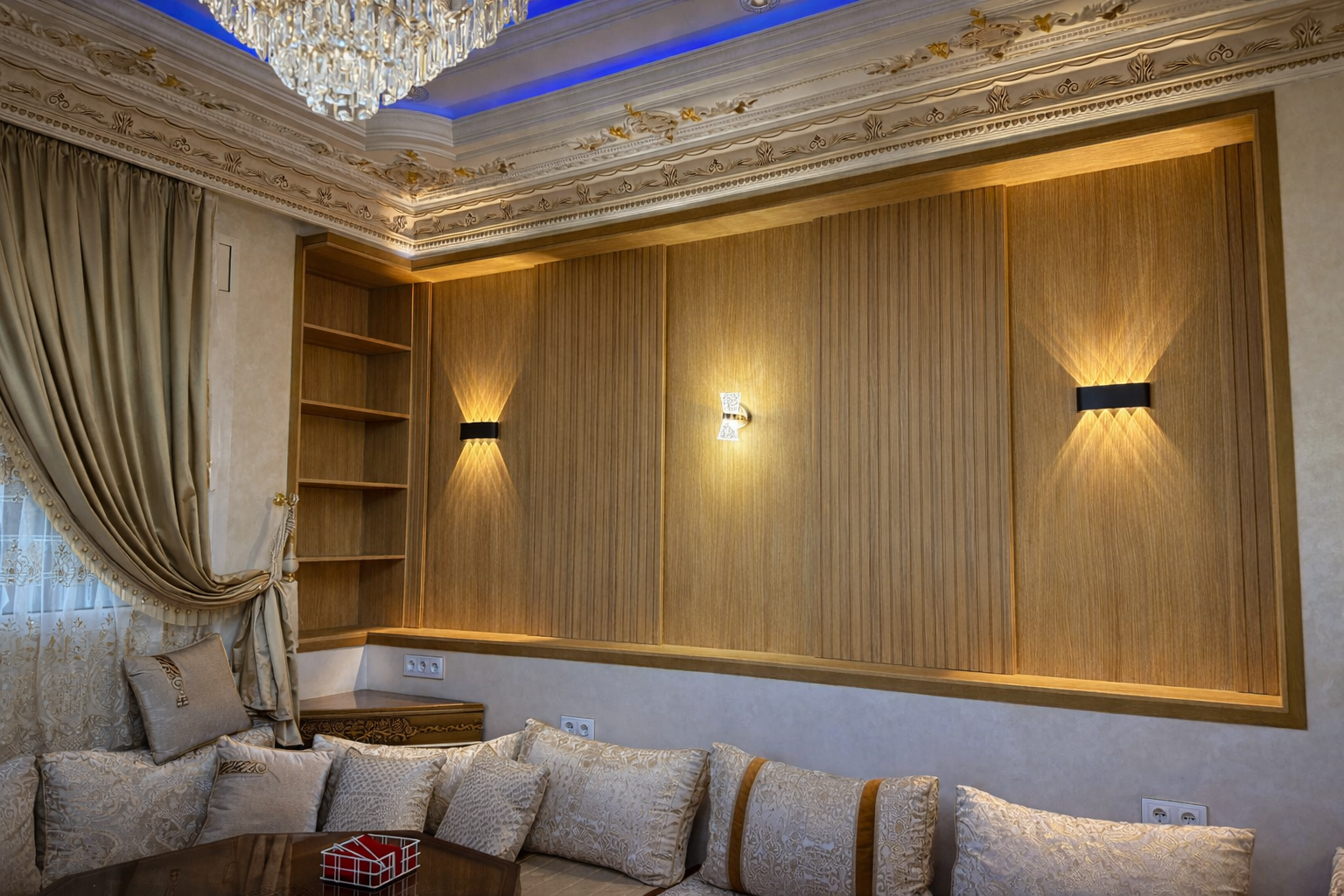 Sala elegante con paredes de madera, cojines decorativos, cortinas de oro y una lámpara de araña brillante en el techo.