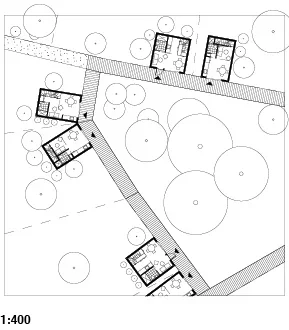 Site plan showing multiple small buildings connected by pathways, surrounded by trees.