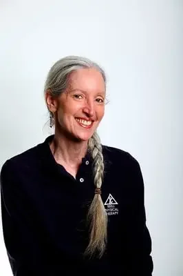 A smiling woman with gray hair in a braid wearing a black shirt with a logo.
