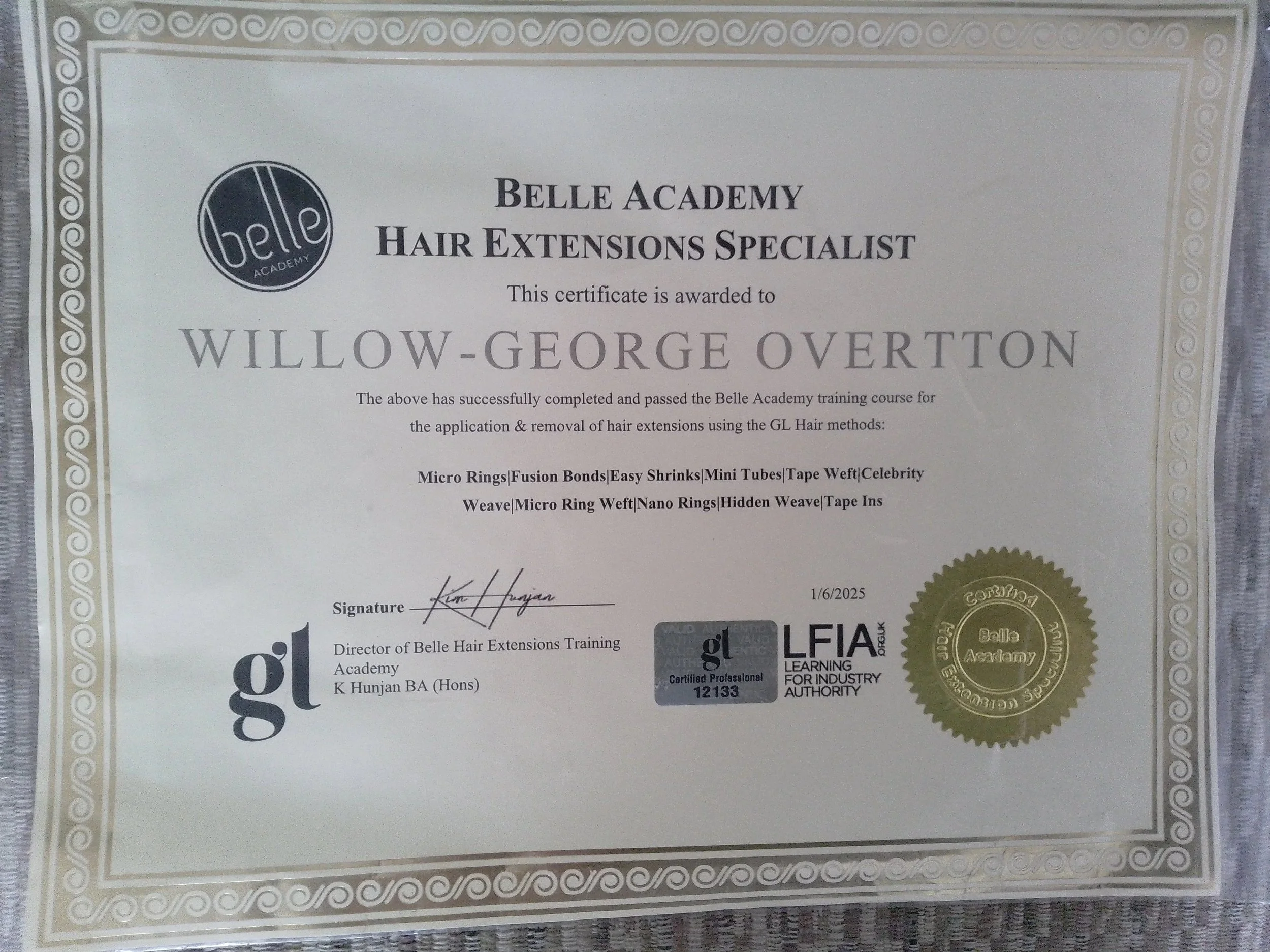 Certificate from Belle Academy awarded to Willow-George Overton for completing hair extension training courses. The certificate has a decorative border, the Belle Academy logo, and a gold seal with signatures.
