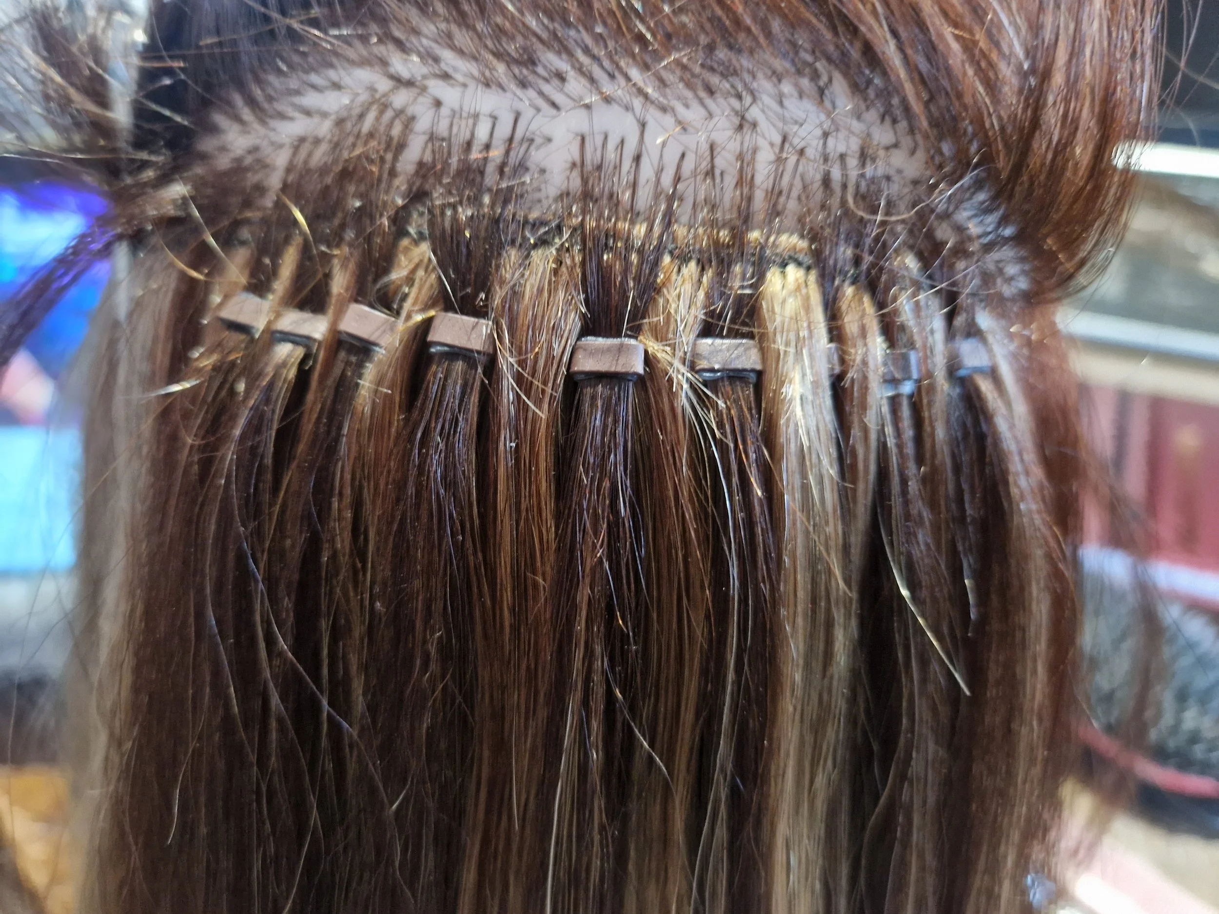 Close-up of a person with brown hair using a curling iron to style their hair.