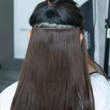 Back view of a woman with straight, shiny brown hair.