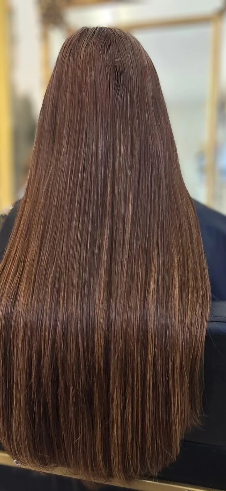 Back of a person with long, straight, shiny, light brown hair.