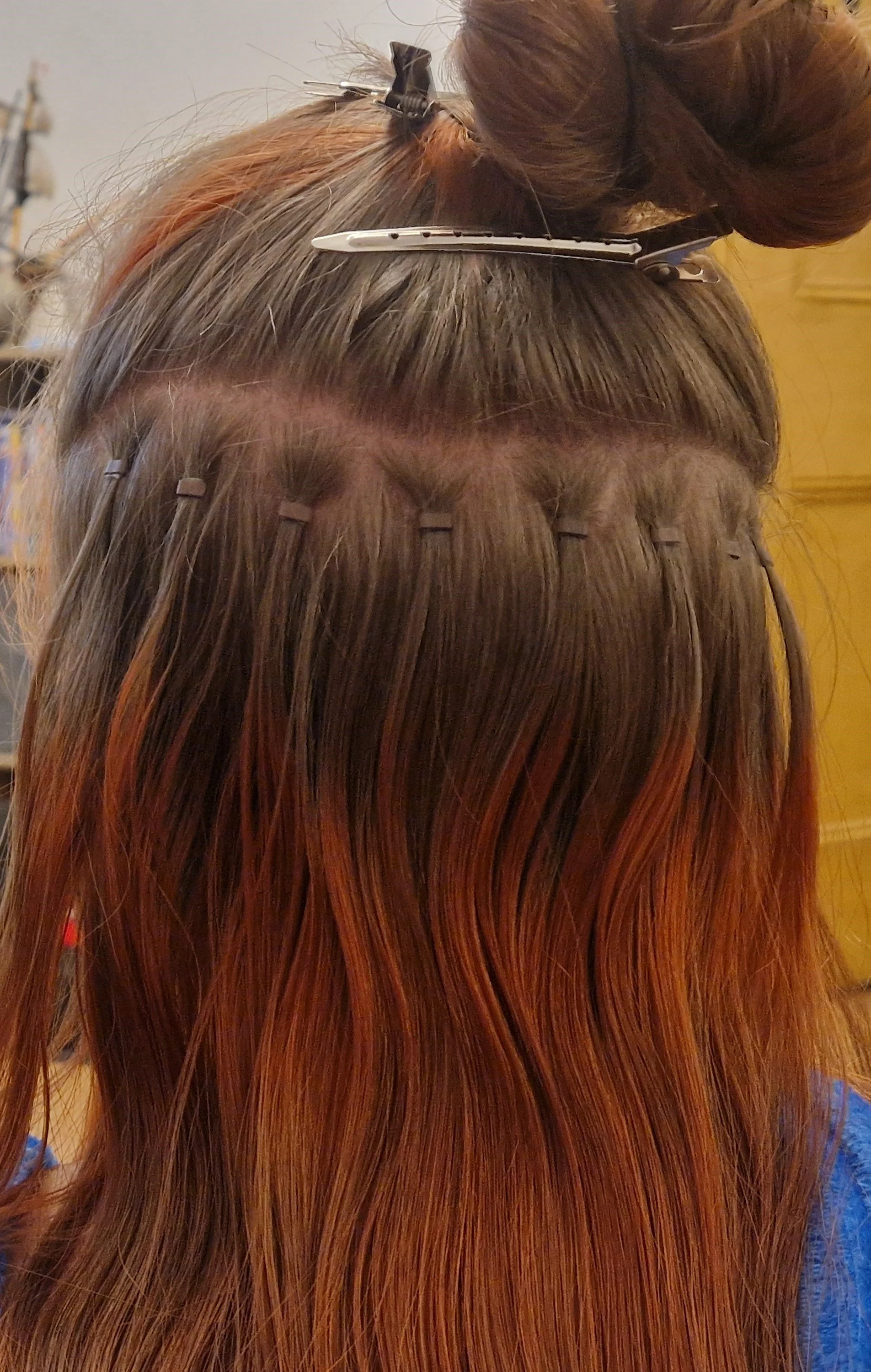 Hair stylist applying a hair color treatment with clips to section hair in a salon.