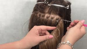 Person getting their hair styled or braided, with hands working on the hair, using tools and accessories.