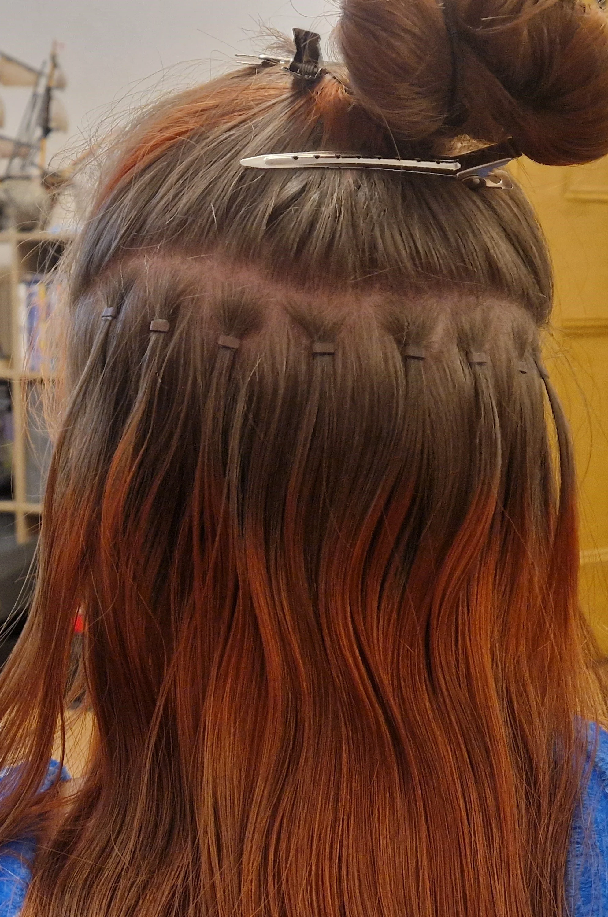 Hairdresser setting hair with clips and curlers, brown hair with reddish highlights.