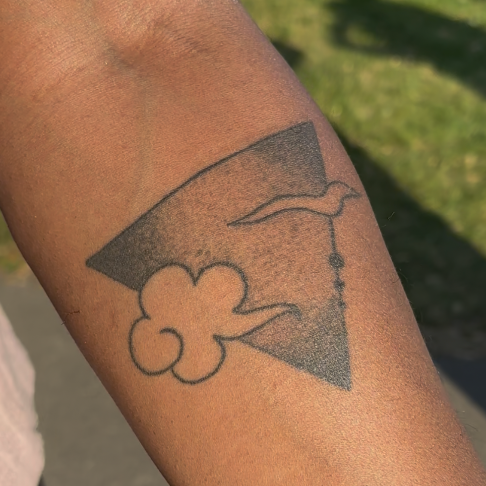Healed geometric tattoo of a triangle with creative cloud inserts, on a person's arm, with darker skin tone.