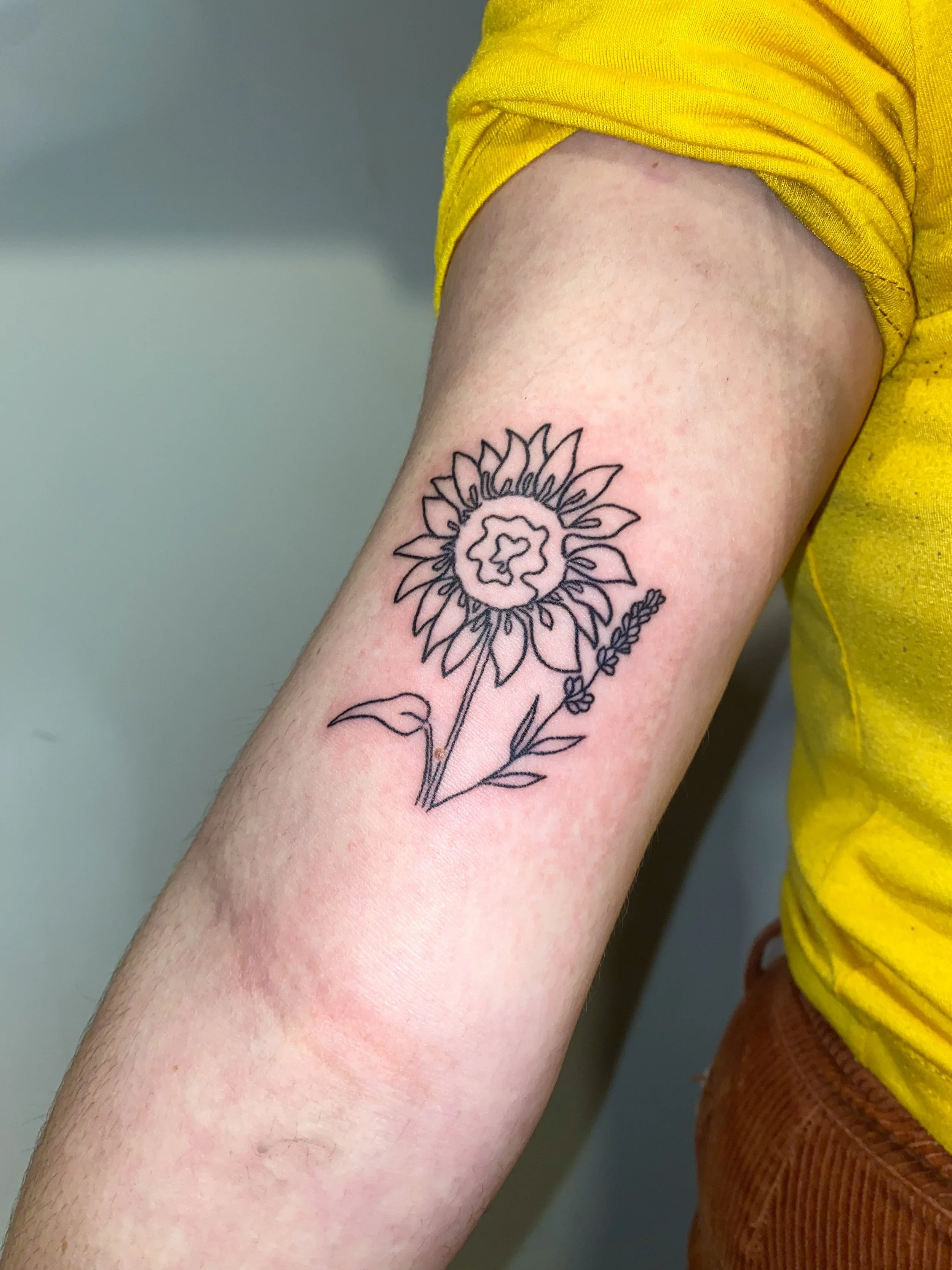 delicate sunflower stick and poke on upper arm bicep