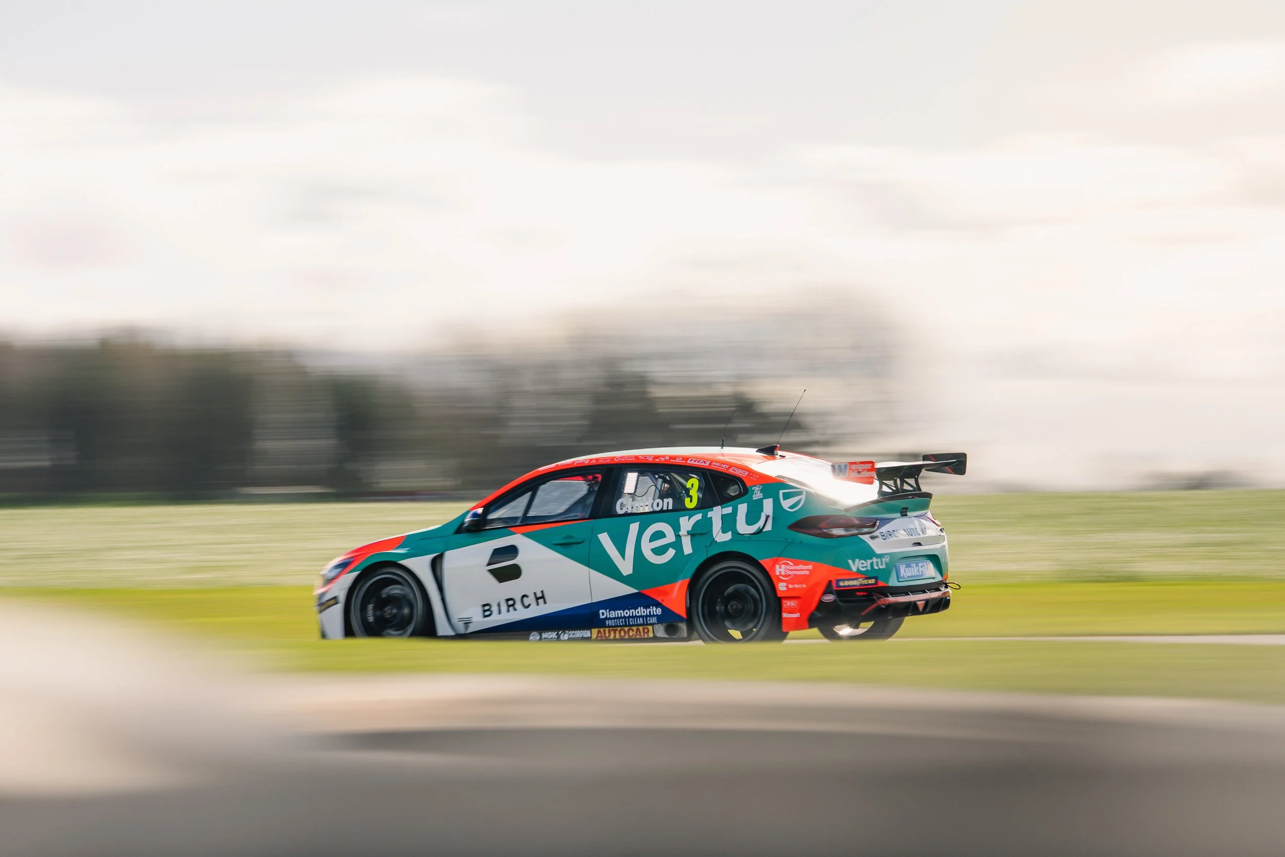 Green and orange BTCC touring car with motion blur at speed during Croft testing
