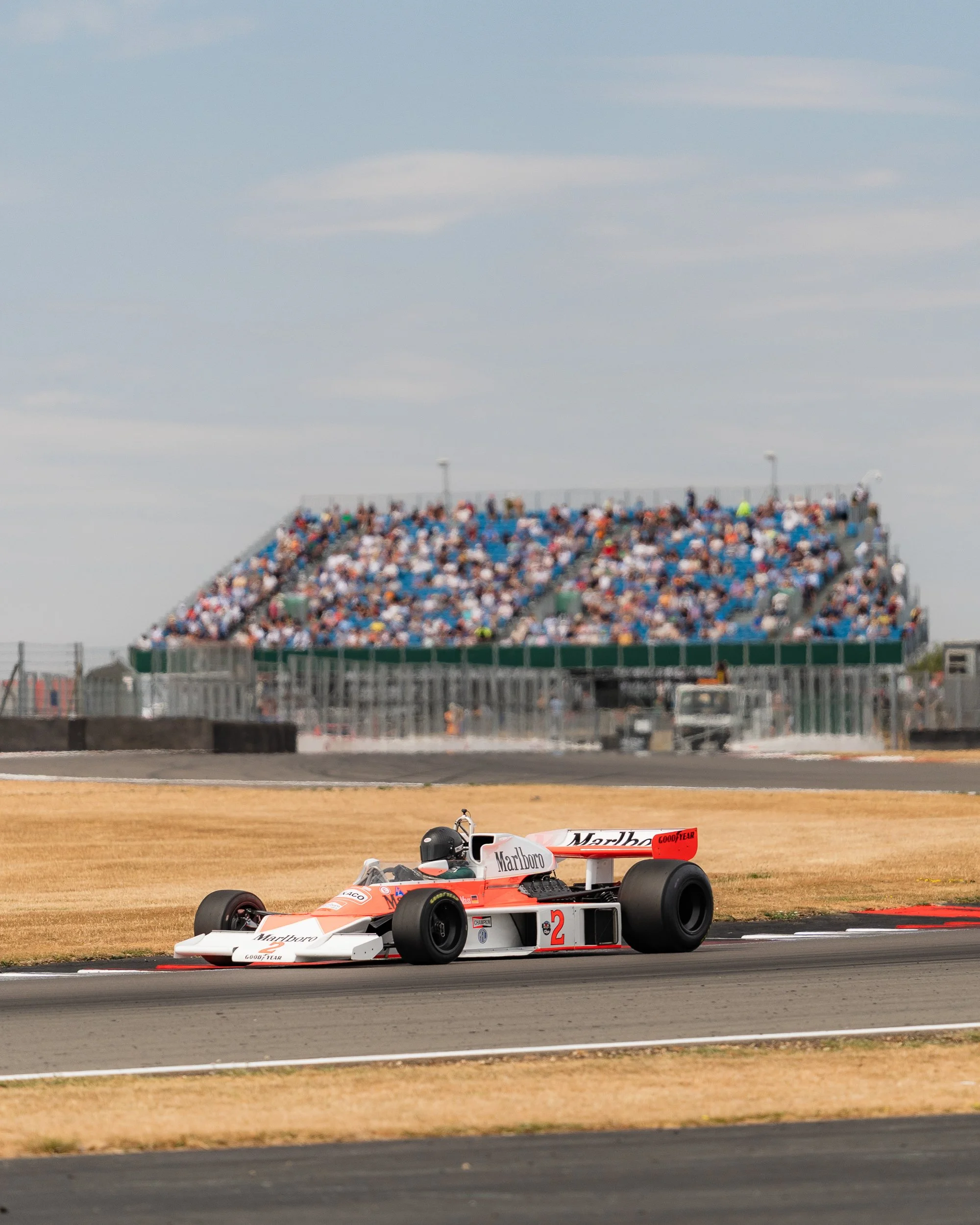 Vintage Formula One car racing past a packed grandstand at the BRDC Classic Silverstone