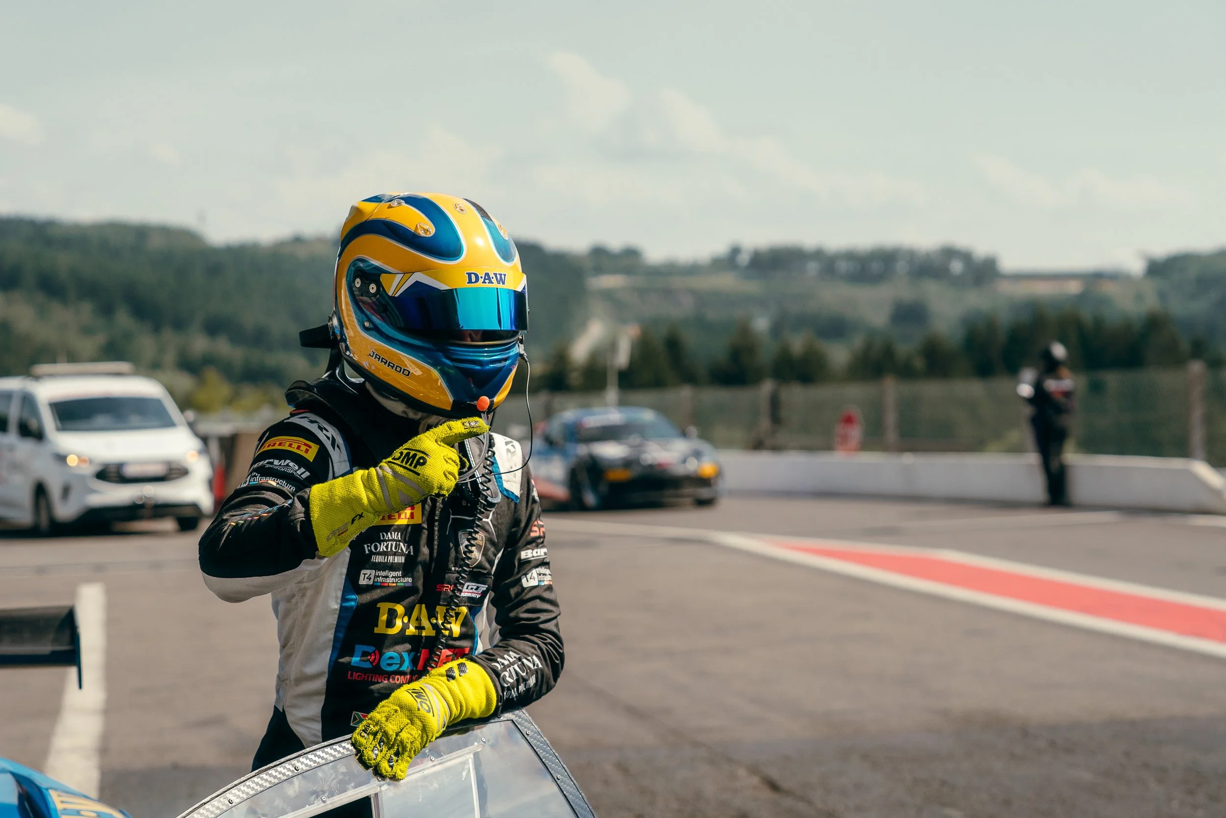 British GT racing driver in helmet and gloves standing in the pit lane at Circuit de Spa-Francorchamps