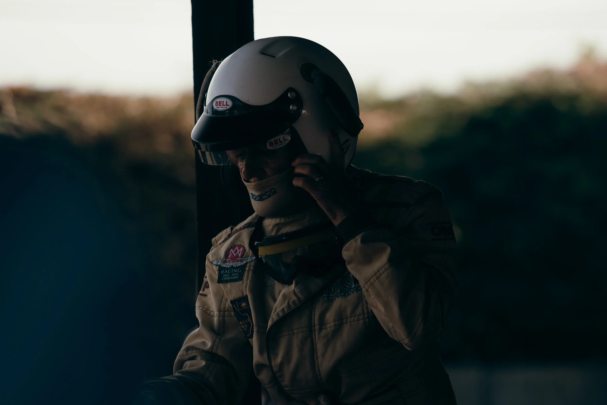 Driver in vintage helmet and period racing overalls fastening chinstrap at Shelsley Walsh Classic Nostalgia