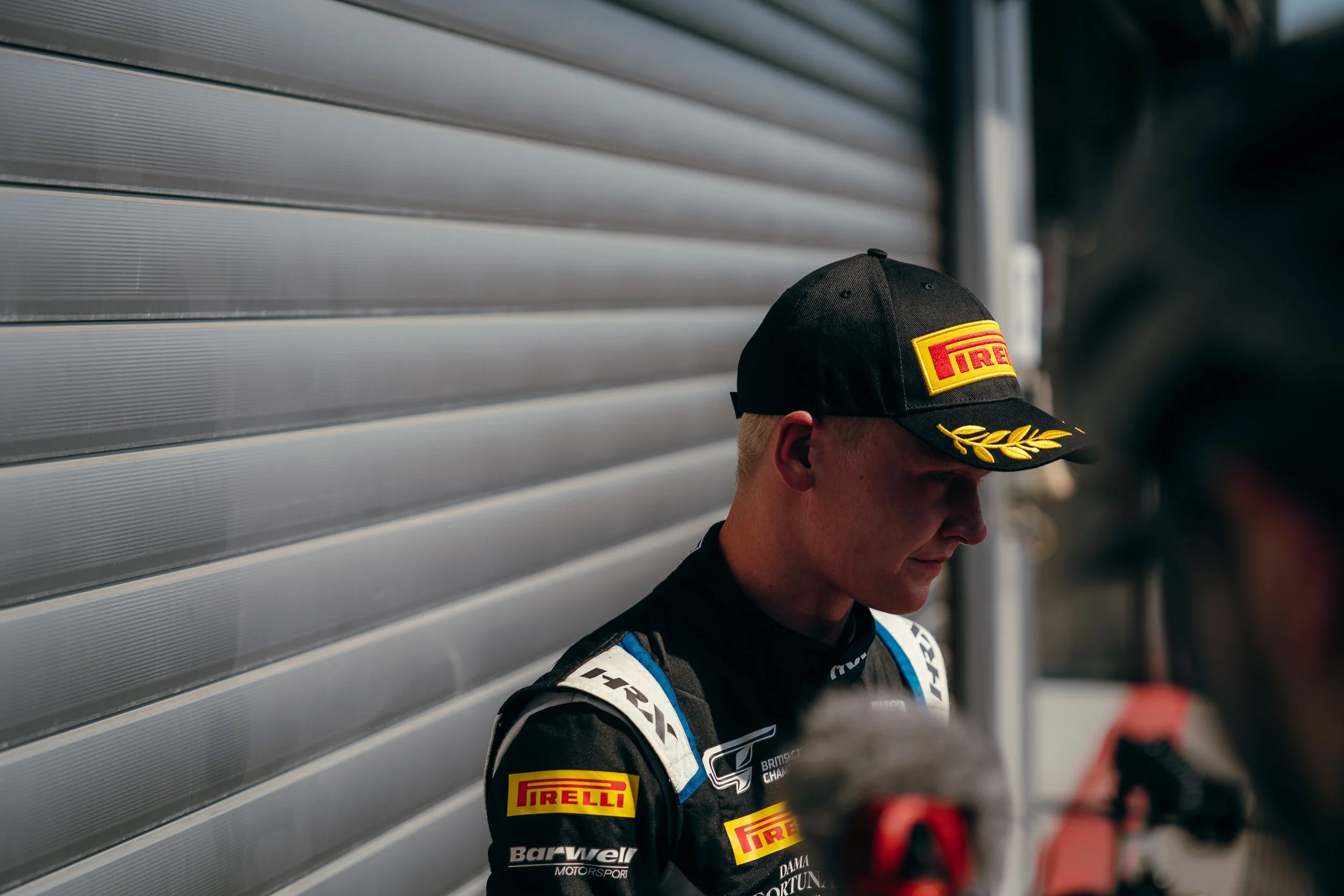 British GT driver in team cap outside the pit garage at Circuit de Spa-Francorchamps