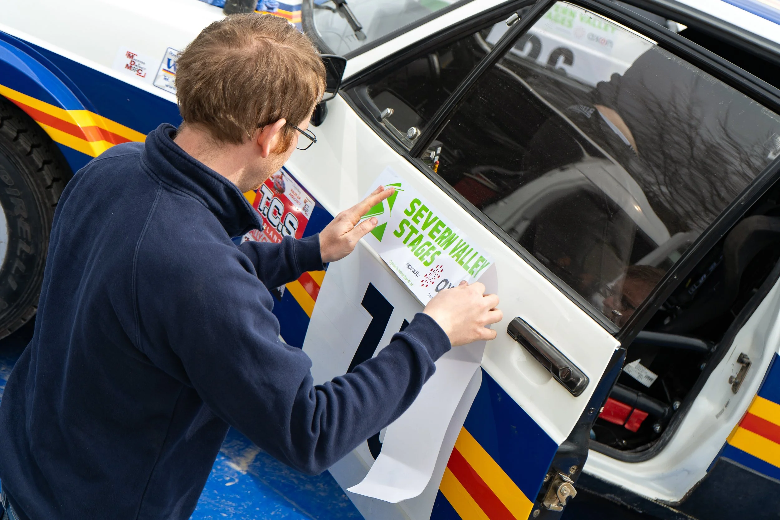 Crew member applying an event stage sticker to a rally car window at the British Rally Championship Severn Valley Stages