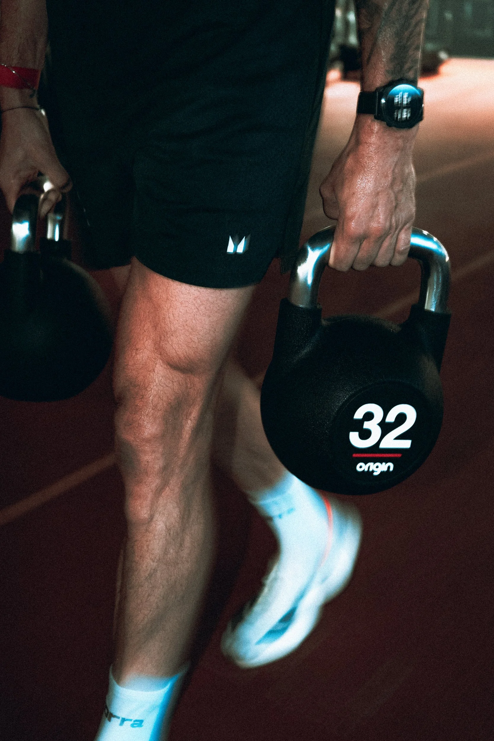 Close-up of an athlete's legs carrying a kettlebell during a farmer's carry exercise, Torra Performance Lilleshall campaign