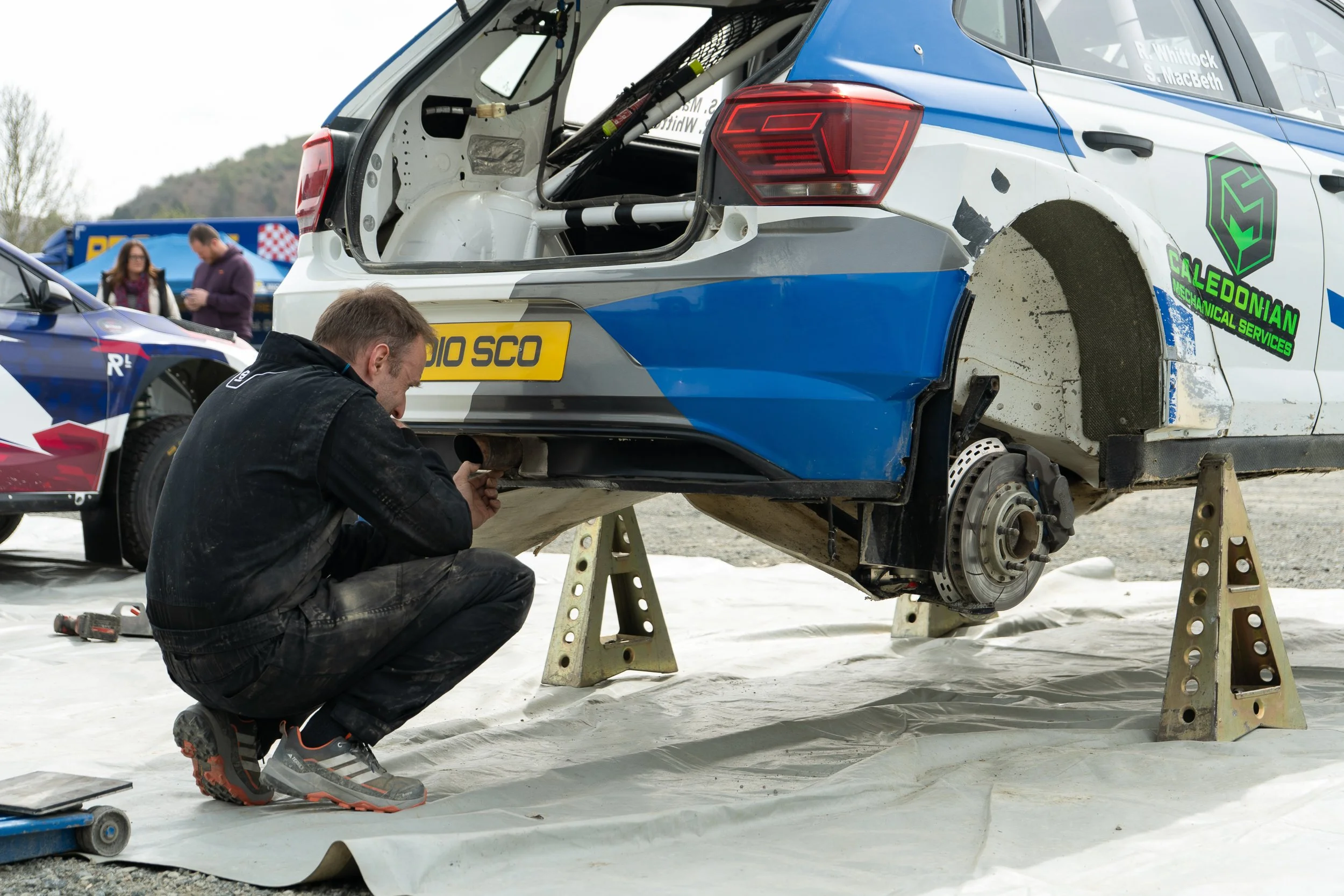 Crew member working on the suspension of a rally car on axle stands at the British Rally Championship Severn Valley Stages
