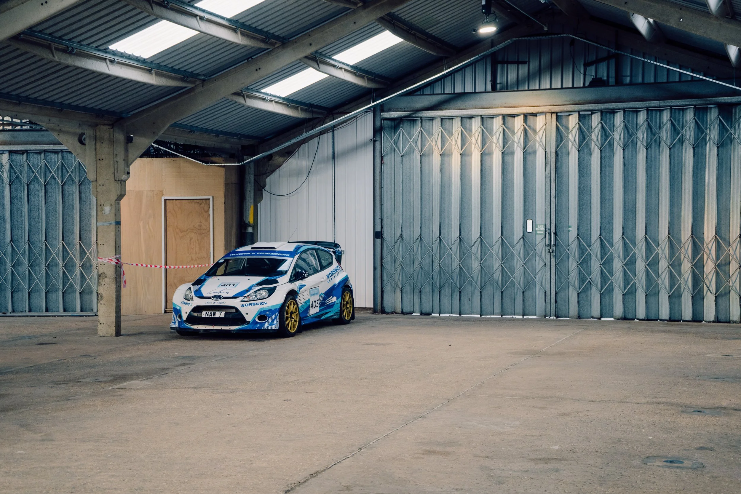 Rally car parked inside a corrugated steel garage unit at Race Retro