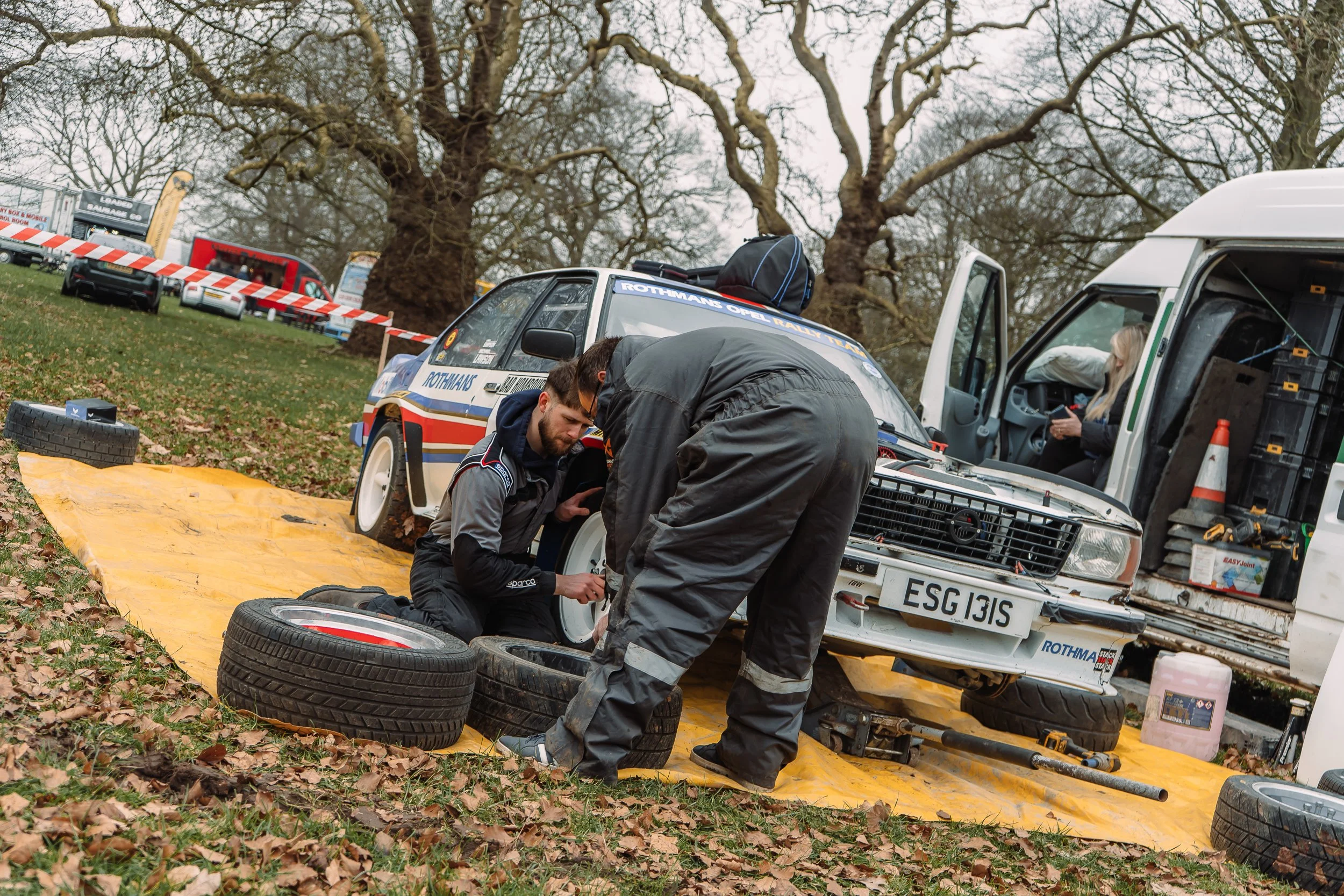 Crew changing tyres beside the rally van in the paddock at the Lombard Rally Festival